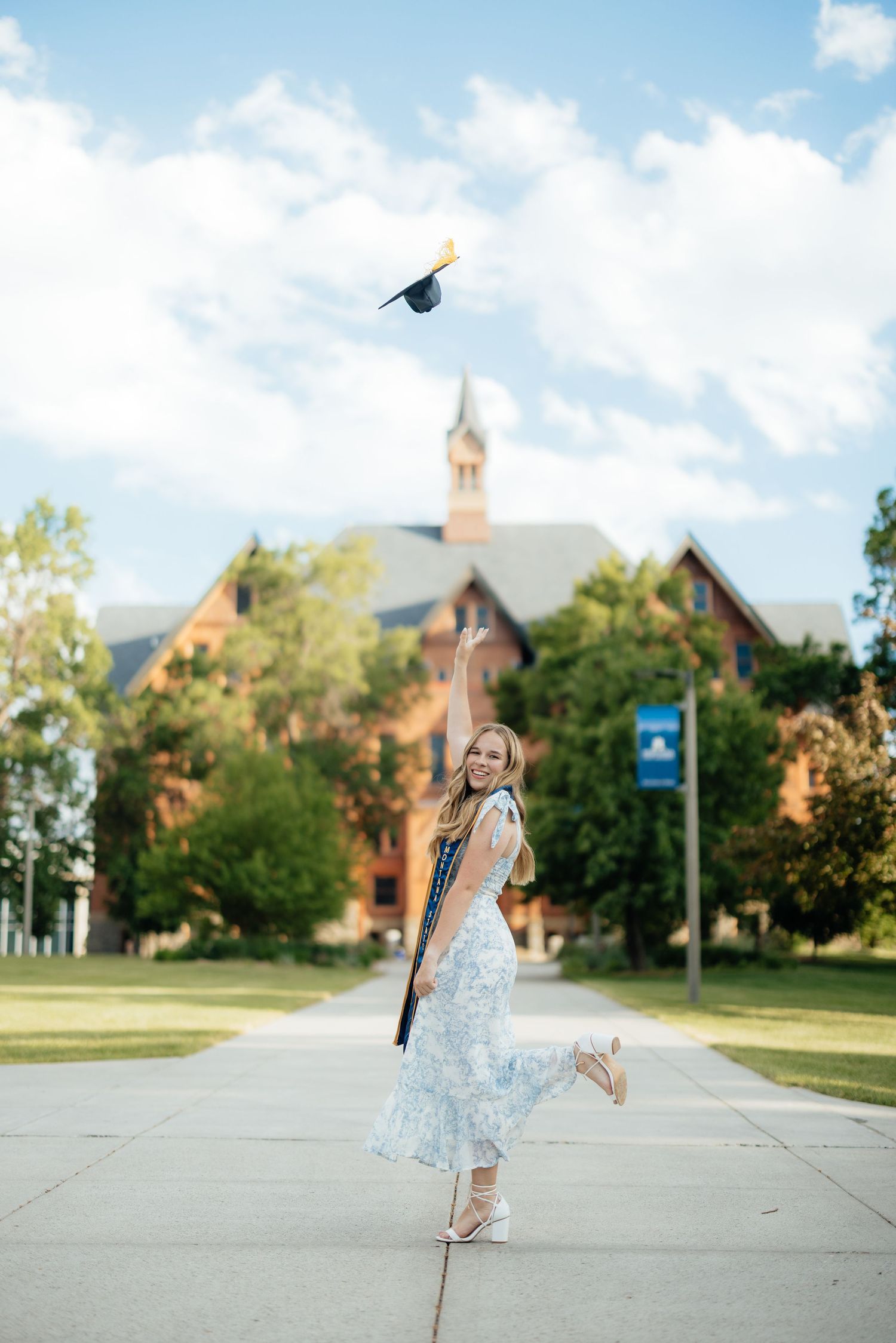 Image of Sierrah Elizabeth throwing her graduation cap in front of Montana Hall. Image by Mallory Jean Photography