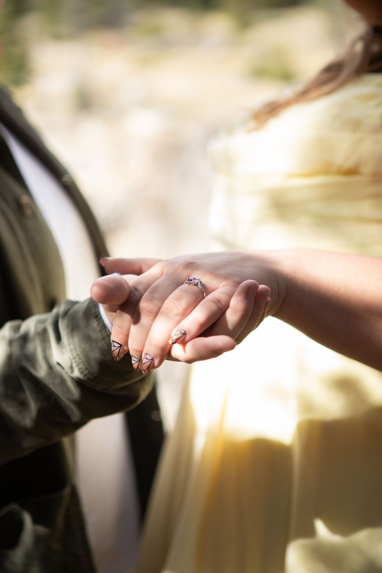 A Bozeman Couple holding hands and showing off their engagement ring for engagement photos at Natural Bridge Falls, Montana.