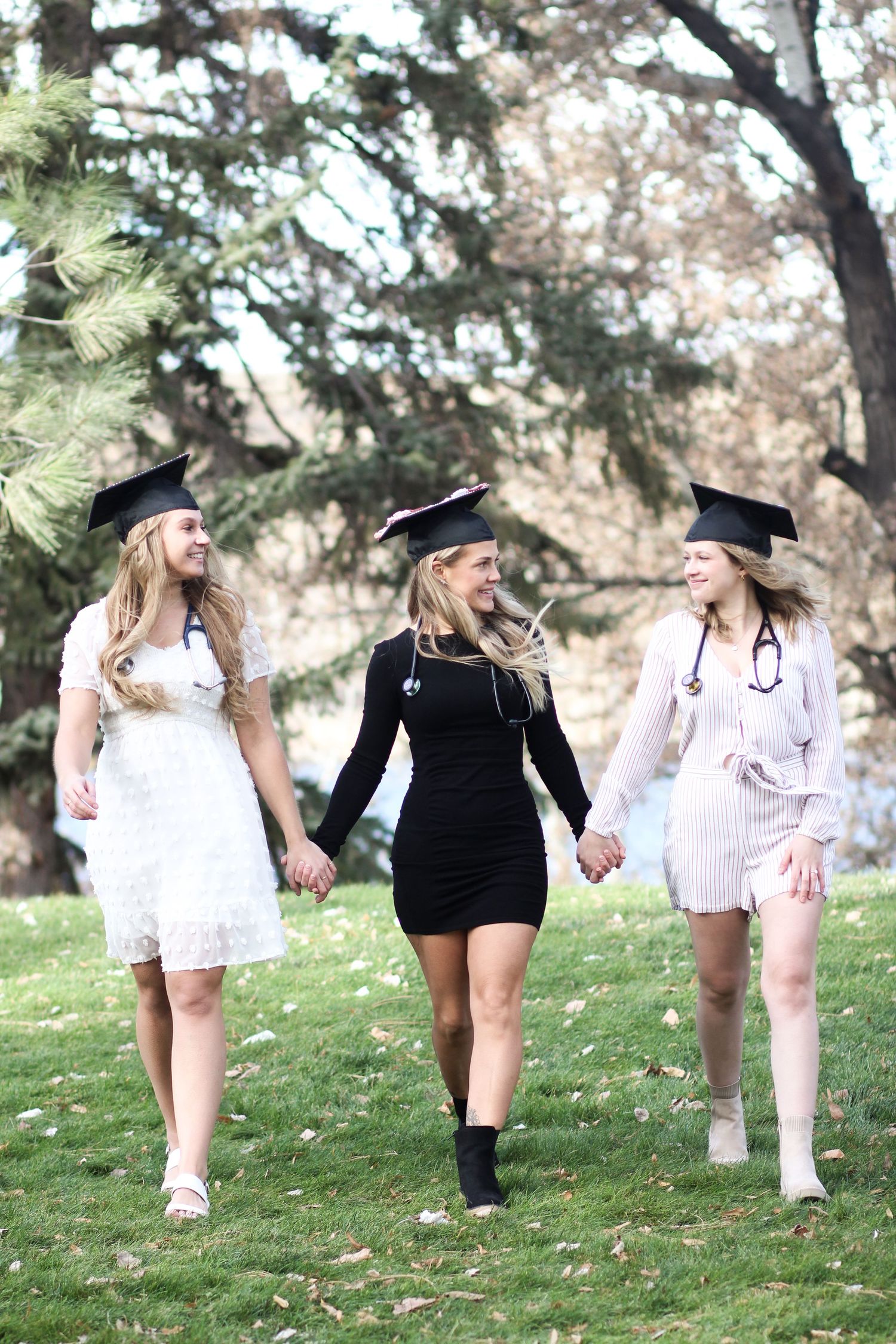 Three Montana State University grads walk together holding hands in Montana.