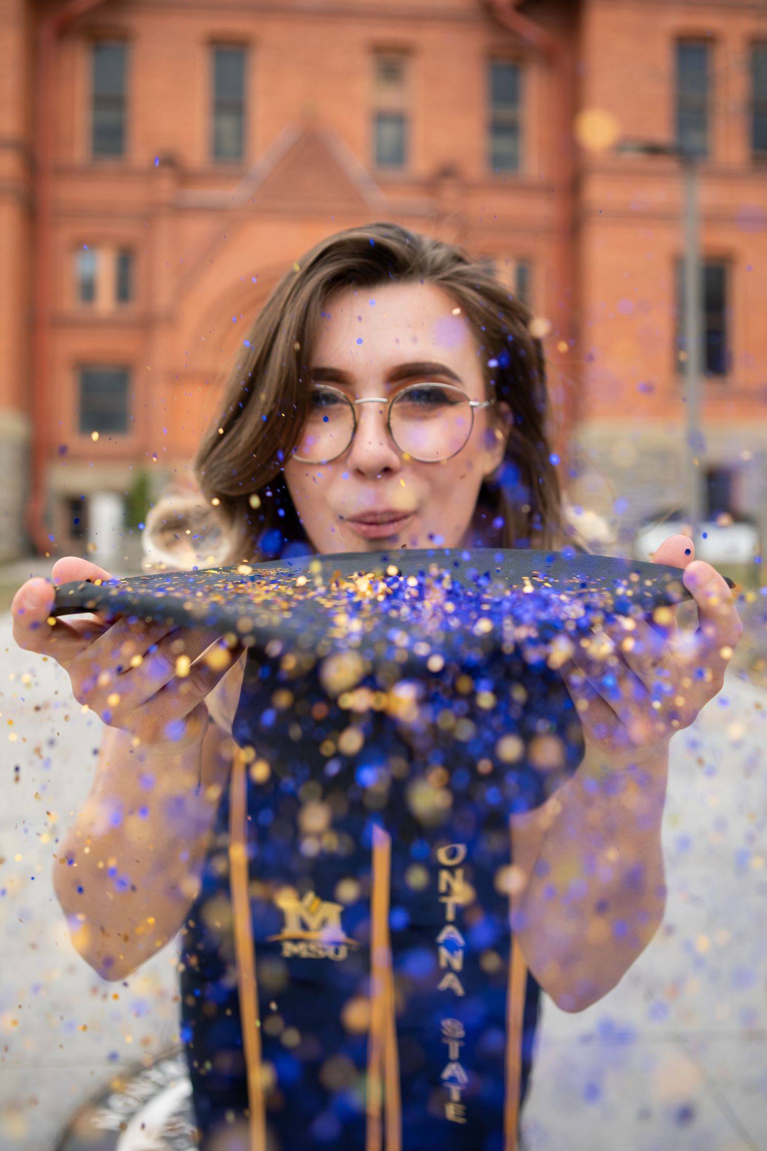 A Montana State University grad blows glitter off their cap in Bozeman, Montana.