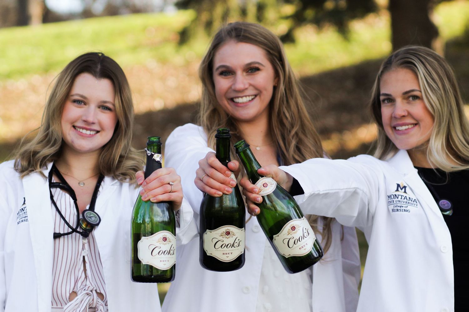 Three Montana State University Grads holds champagne bottles in a toast in Great Falls, Montana.