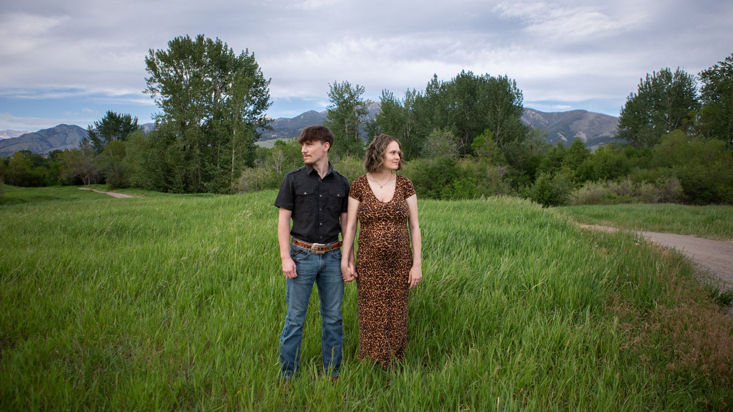 A Bozeman couple stands together holding hands in front of the Bridger Mountains.