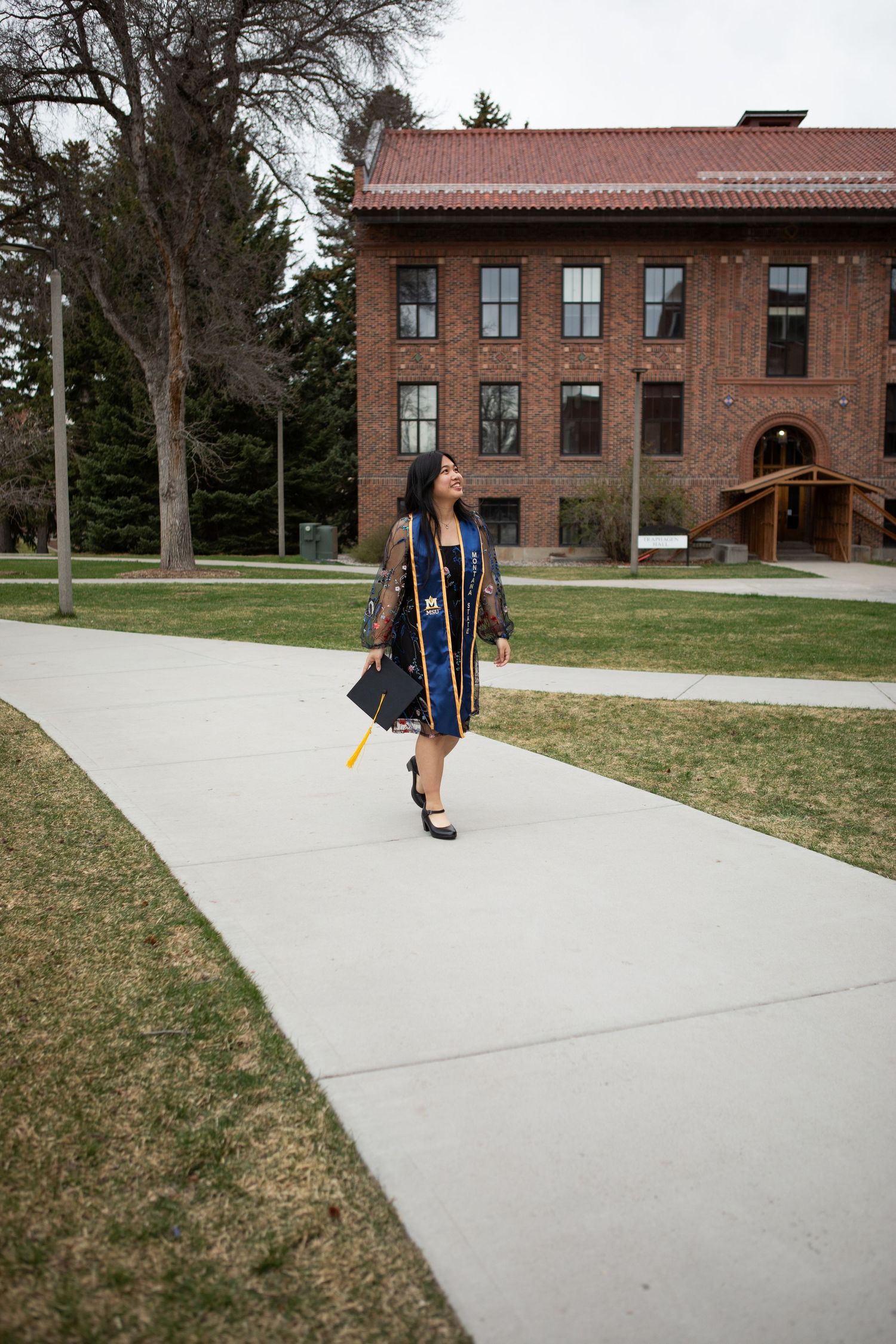 A Montana State University Grad walks on a path near Traphagen Hall in Bozeman, Montana.