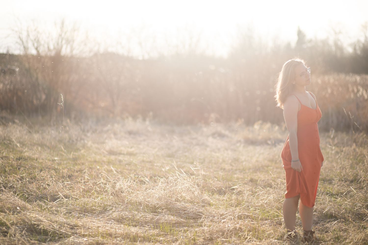A Bozeman Senior standing in the field with sun flair in the background.