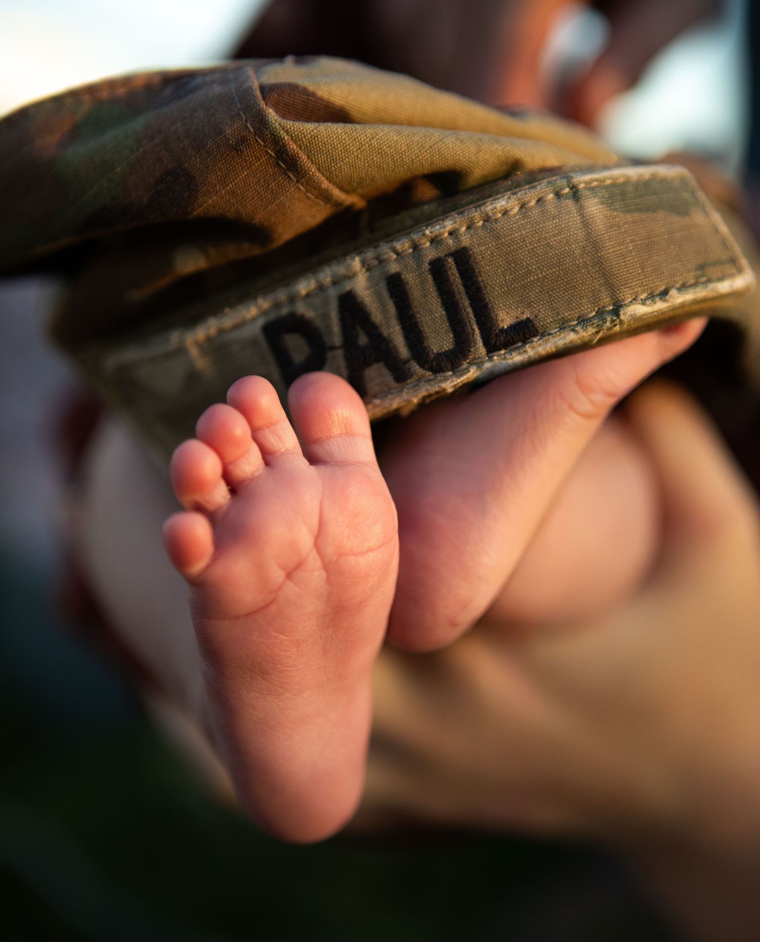 A Bozeman baby's feet with their dad's military cap sitting on top of them.