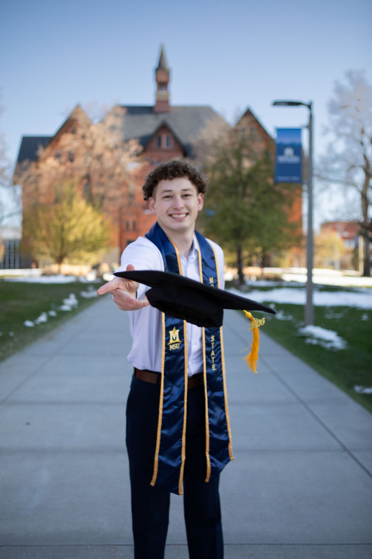 A Montana State University Grad throws his cap in front of Montana Hall in Bozeman, Montana.