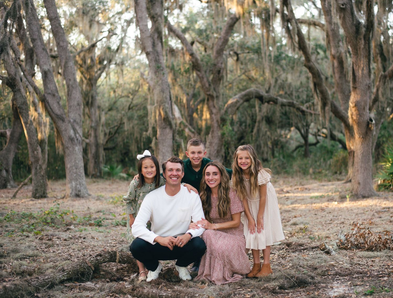 A group poses together in a wooded area with eucalyptus trees and natural lighting during golden hour.