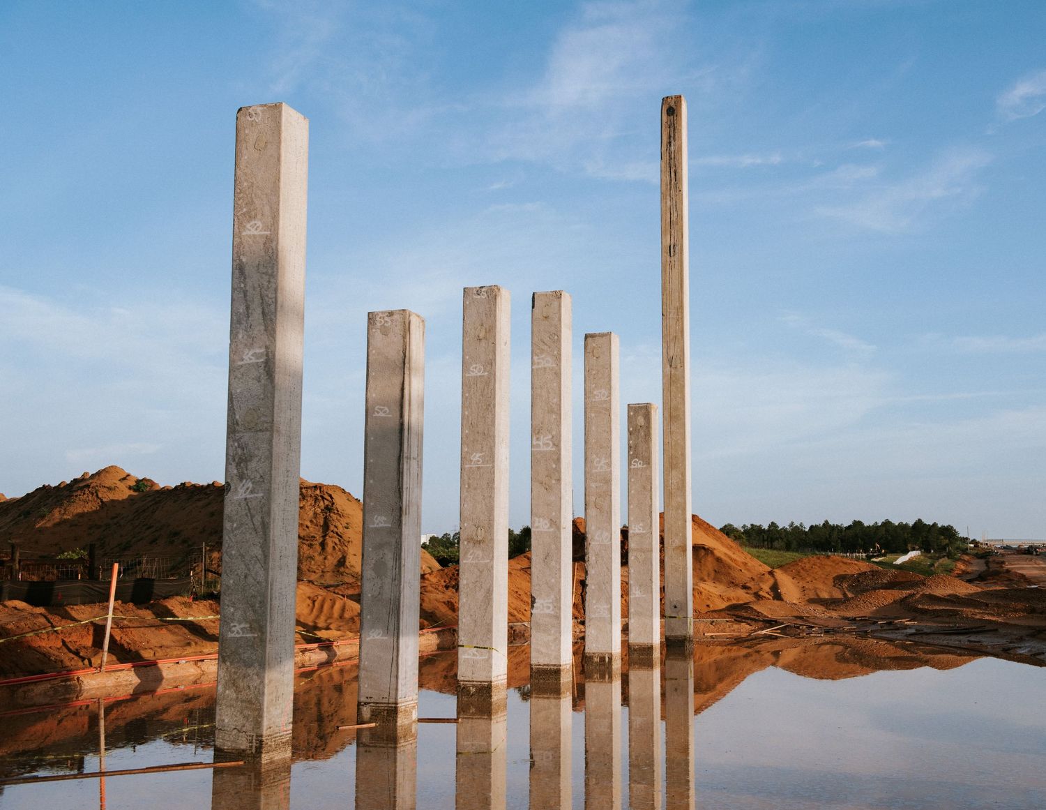 Modern architectural installation with reflective steel pillars in desert landscape.