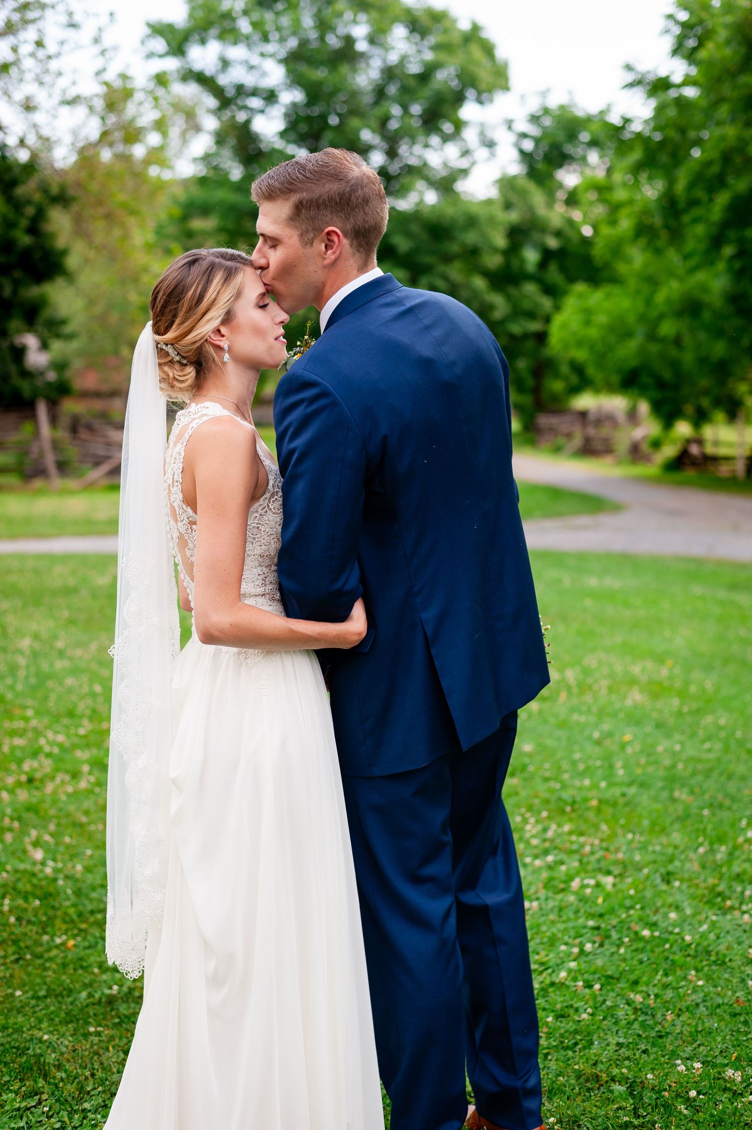 Intimate wedding moment captured on grassy field with couple in traditional attire.