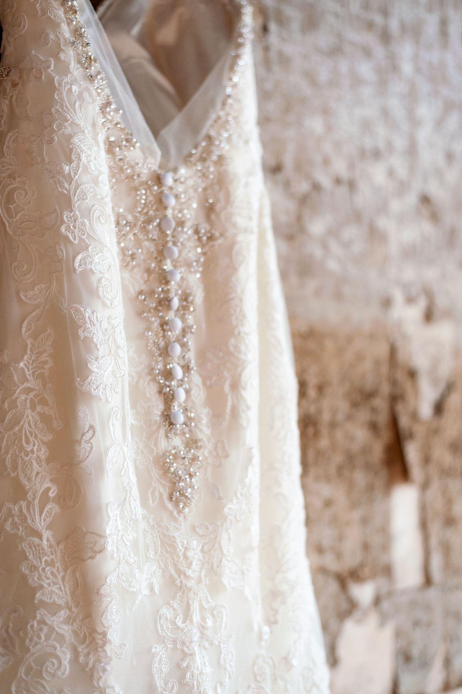 Close-up of intricate beaded lace pattern on ivory wedding gown bodice.