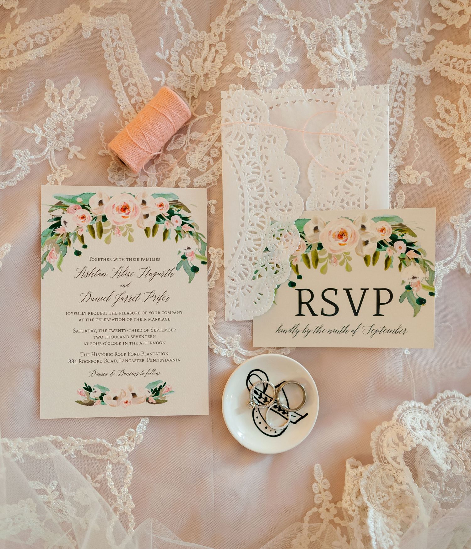 Wedding invitation suite with floral details and RSVP card on lace background.