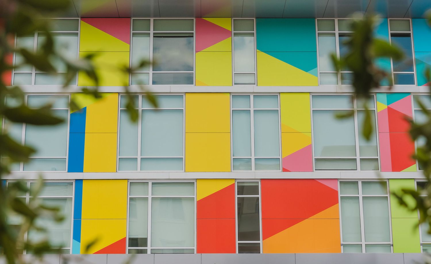 A colorful retro motel exterior with Pixon signage features vibrant geometric patterns painted across its facade.