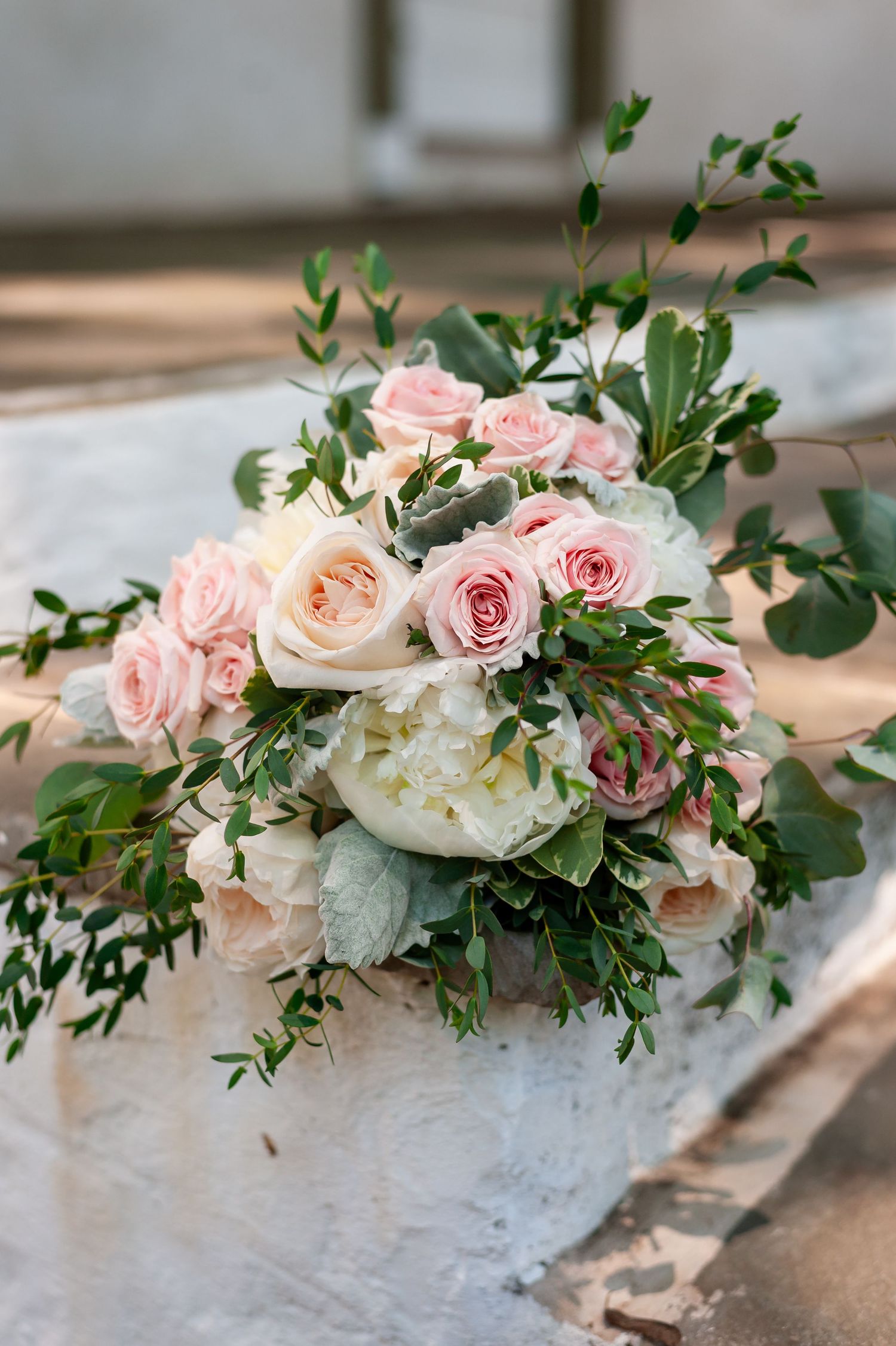 Elegant bridal bouquet with pink roses, white peonies and eucalyptus on white surface.