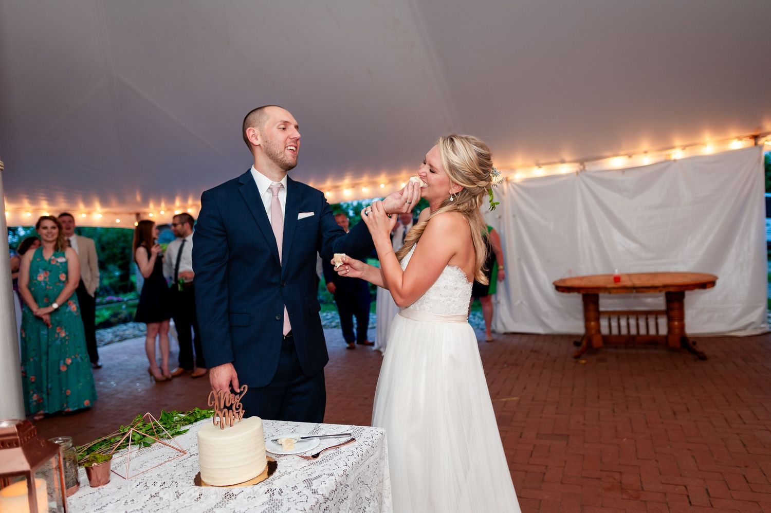 Newlyweds laughing together during their wedding cake cutting ceremony.