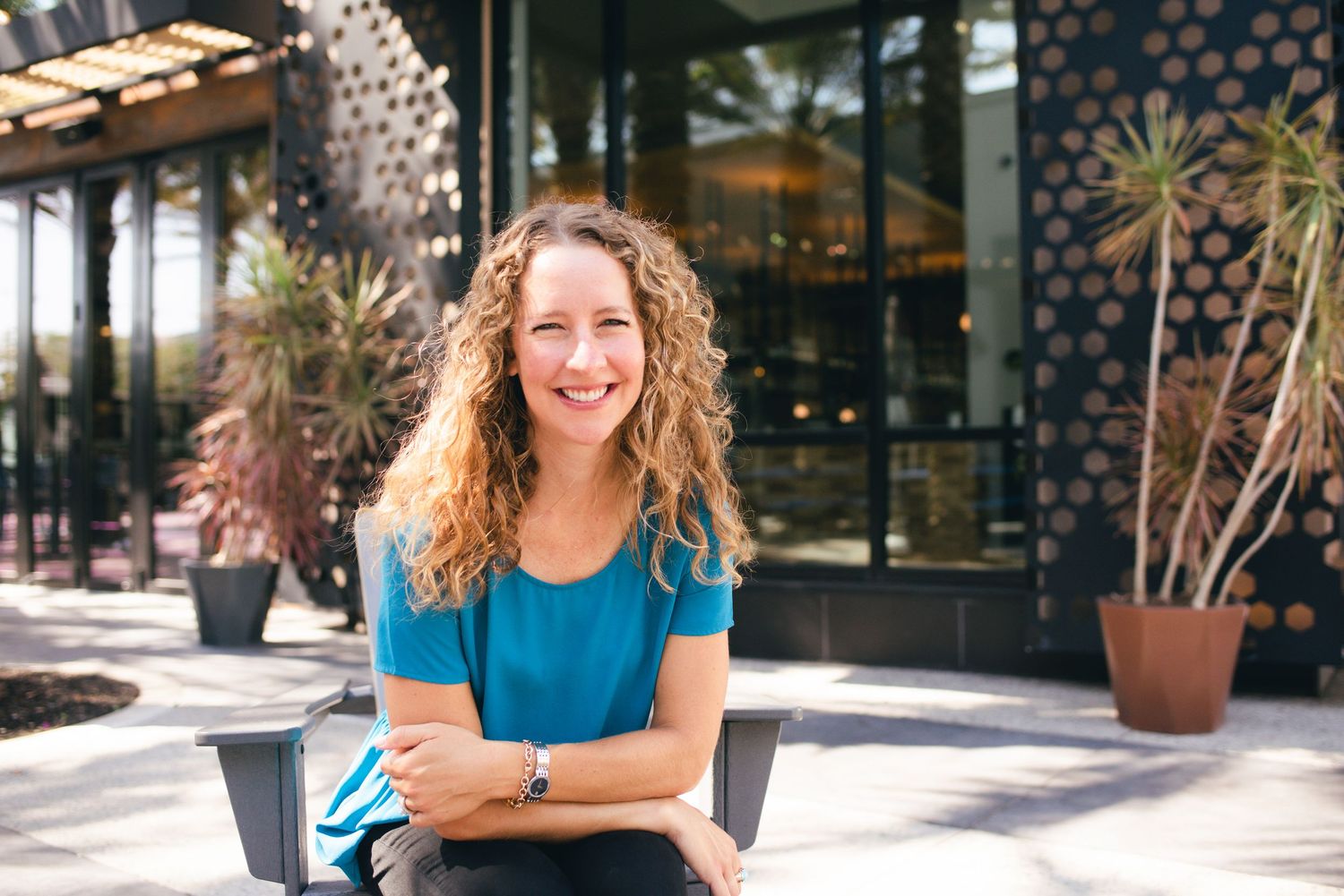 Casual outdoor business portrait with arms crossed in front of retail space.
