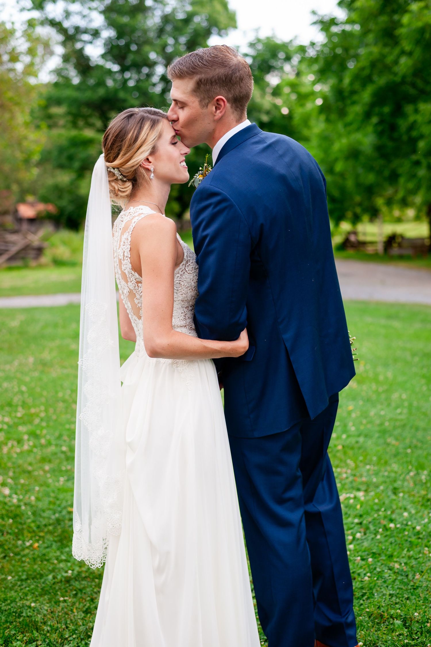 Romantic wedding portraits in a garden setting with couple in white dress and navy suit.