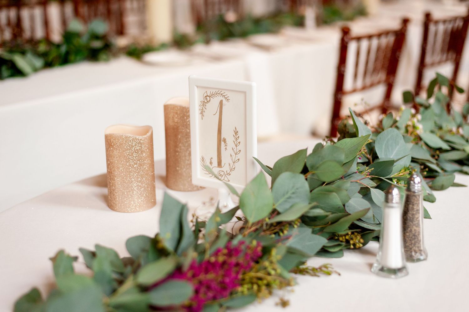 Wedding table decor featuring gold candles and eucalyptus garland centerpiece.