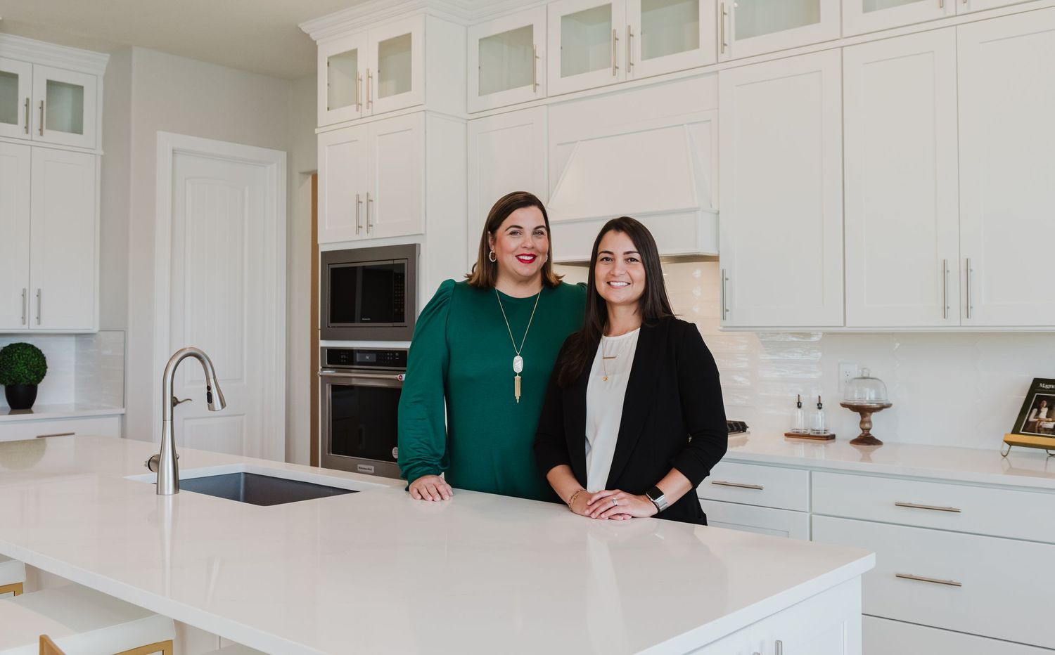 Two colleagues posing together at white marble kitchen island.