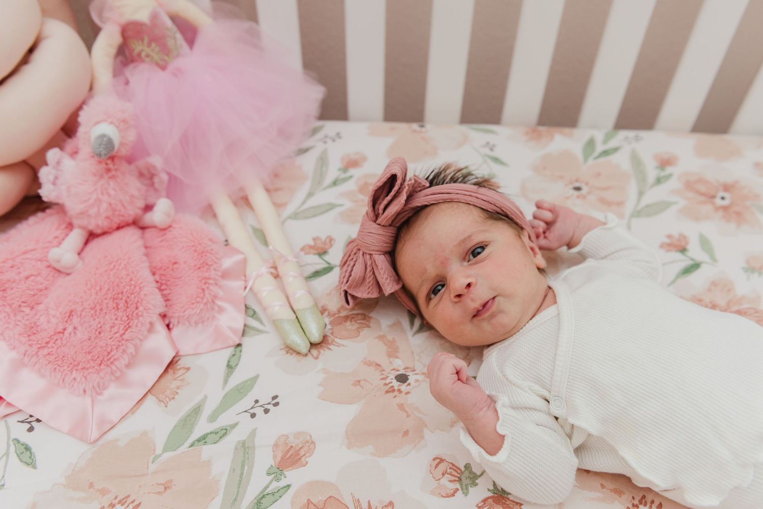 Floral crib bedding with pink plush toys in a nursery setting.
