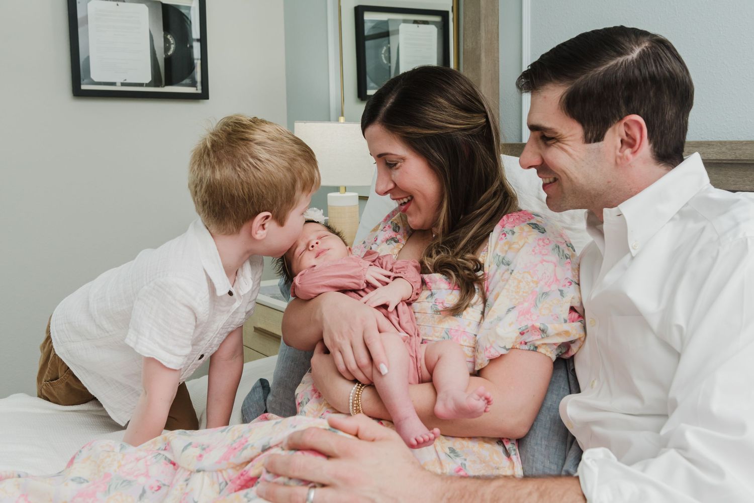Sweet family moment captured as toddler interacts with newborn sibling while parents smile.