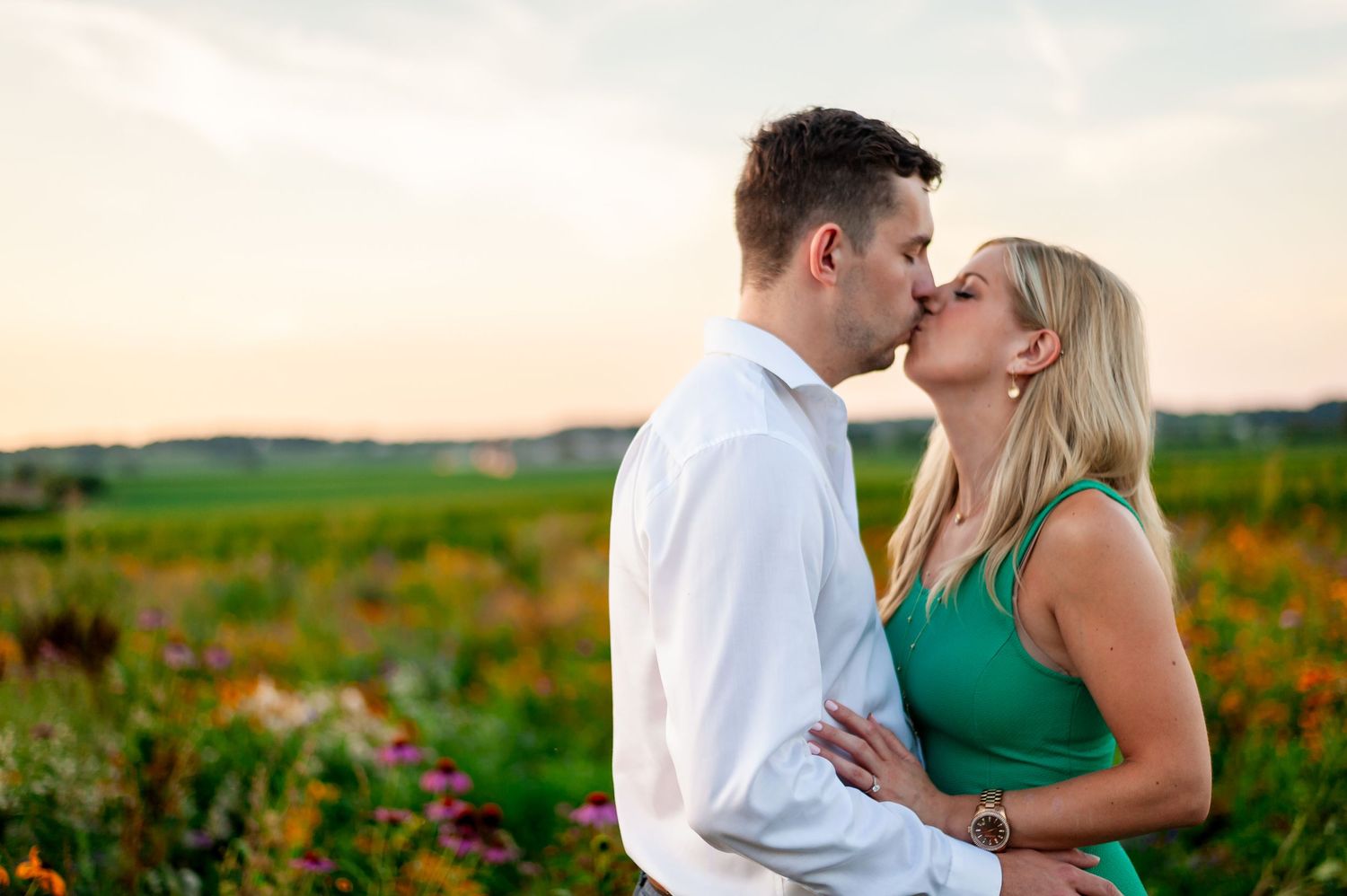 Tender moment between couple during sunset photoshoot in flowering meadow.