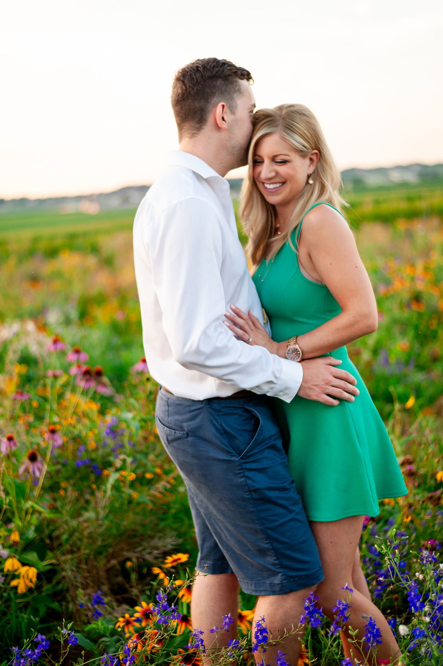 Happy couple laughing together surrounded by purple and yellow wildflowers in a summer field.