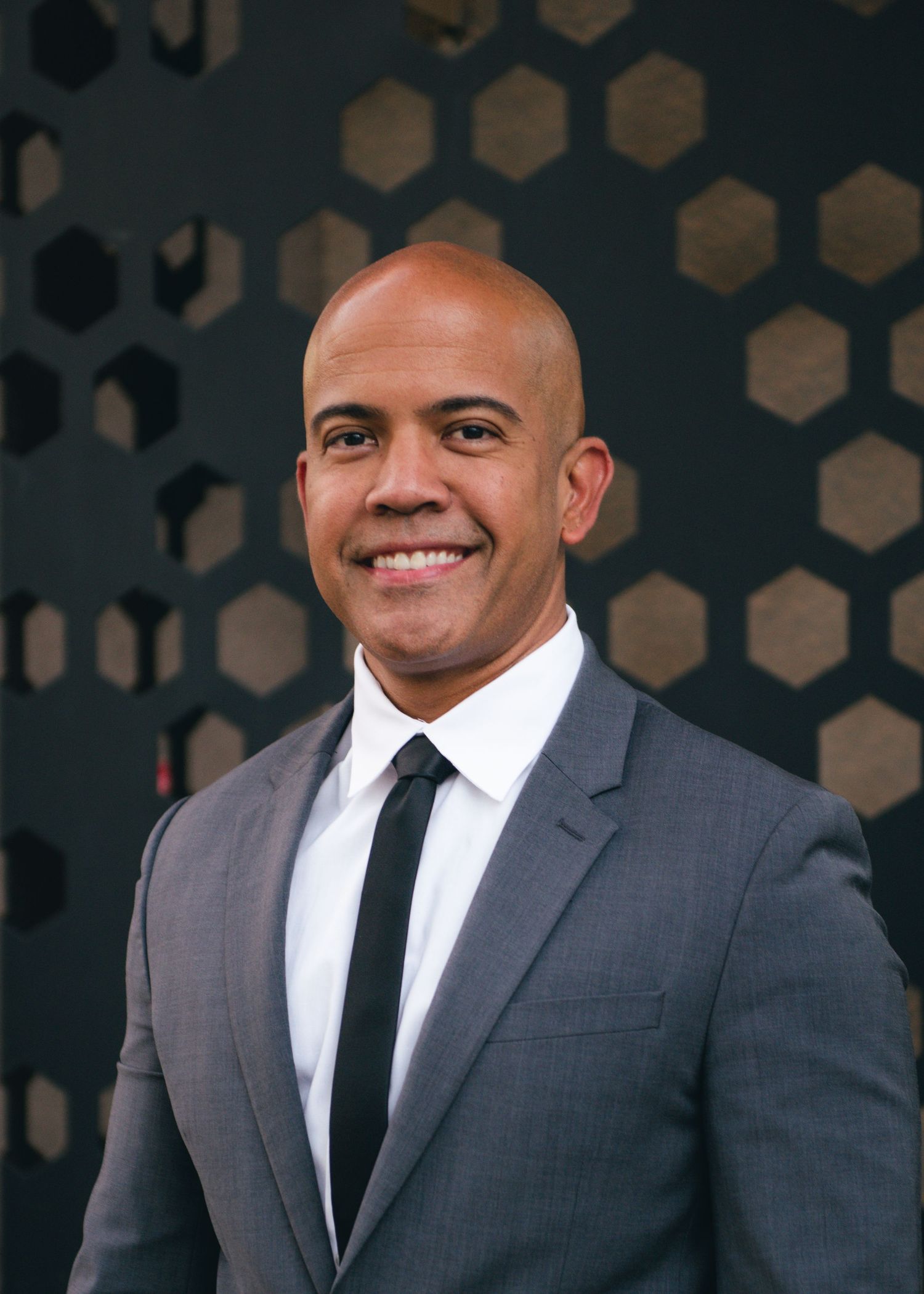 Studio portraits with a geometric pattern background showing confident poses in formal attire.