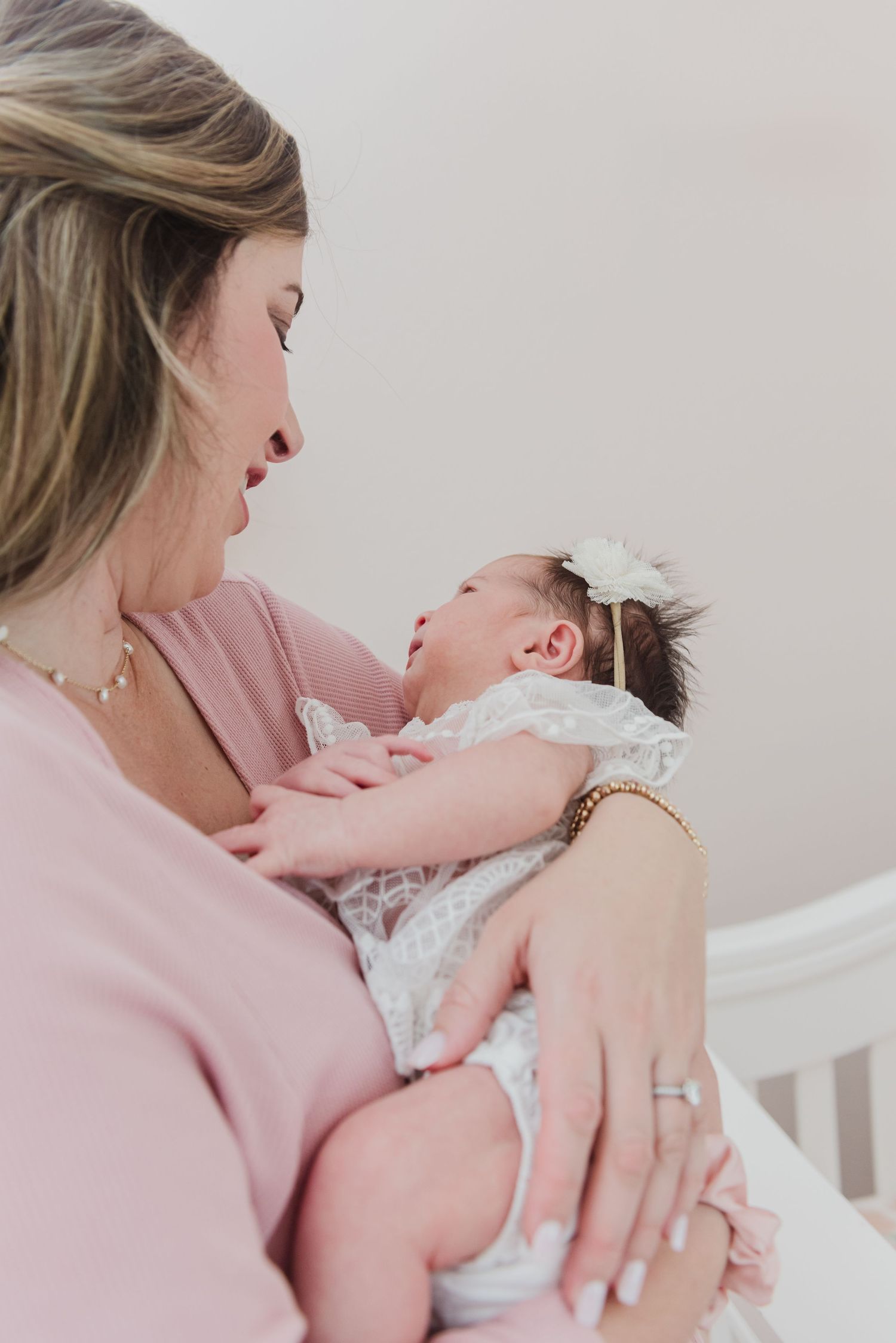 Tender moment captured in soft pink tones in nursery setting.