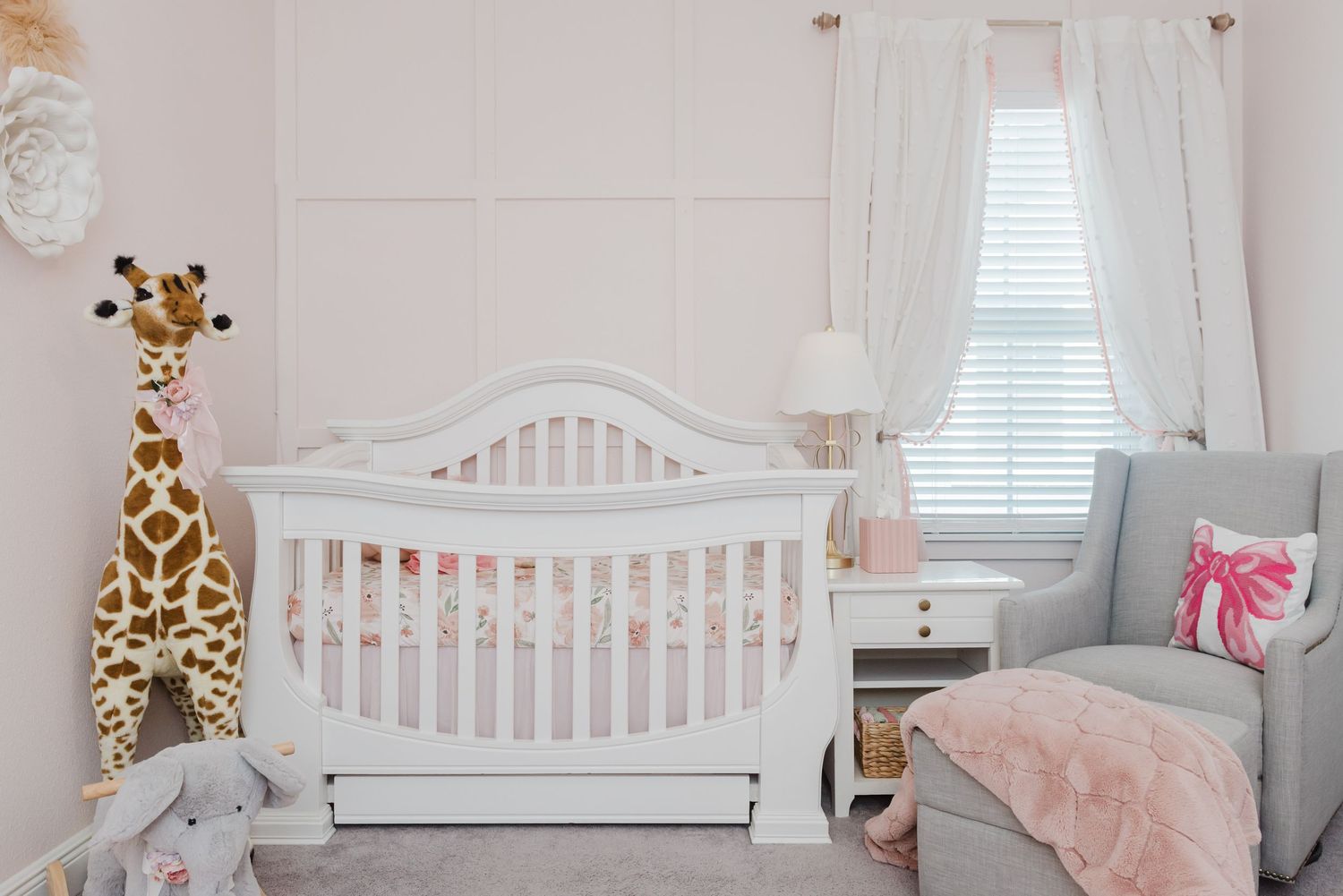 Soft pink nursery room with white crib and delicate decor against light walls.