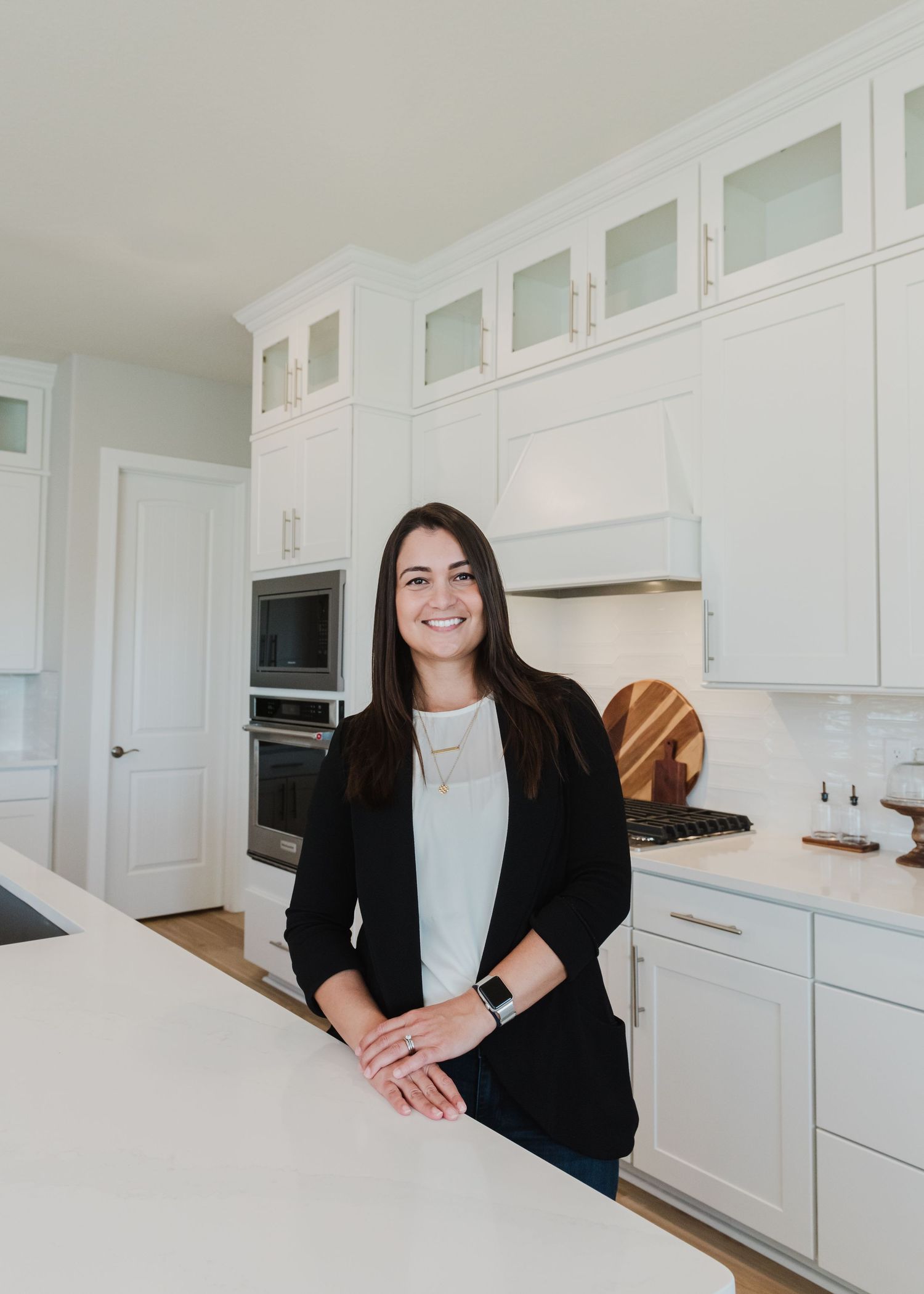 Business professional leaning on white countertop in contemporary kitchen setting.