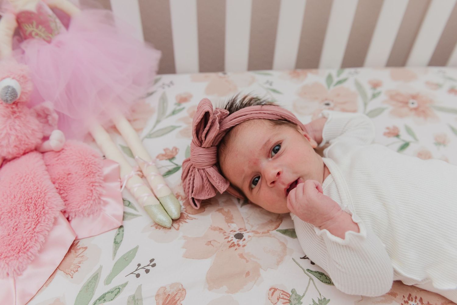 Sweet nursery scene with floral bedding and pink plush toys.