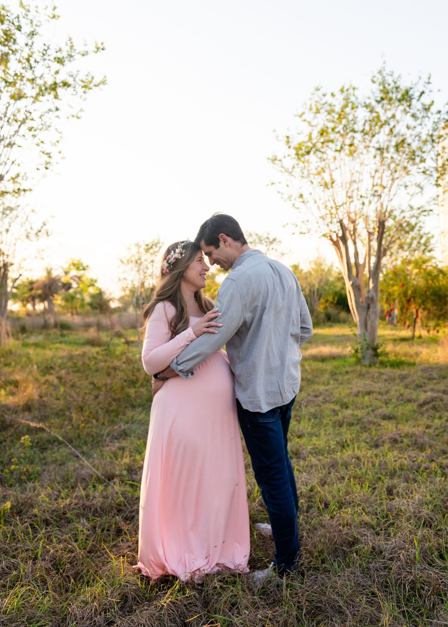 A couple shares a tender romantic moment in a field at sunset, bathed in warm golden light.
