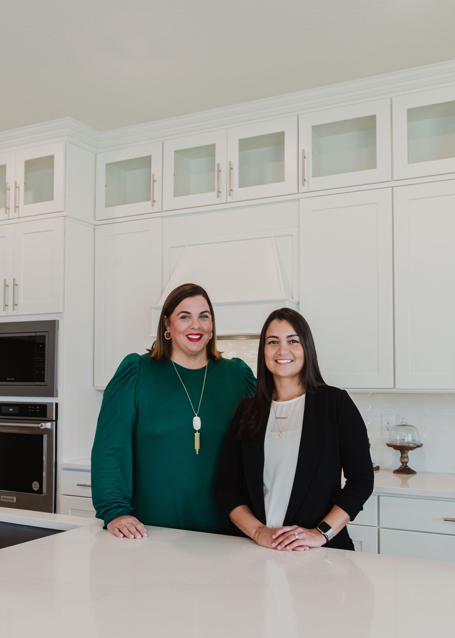 Two business partners smiling in upscale white modern kitchen.
