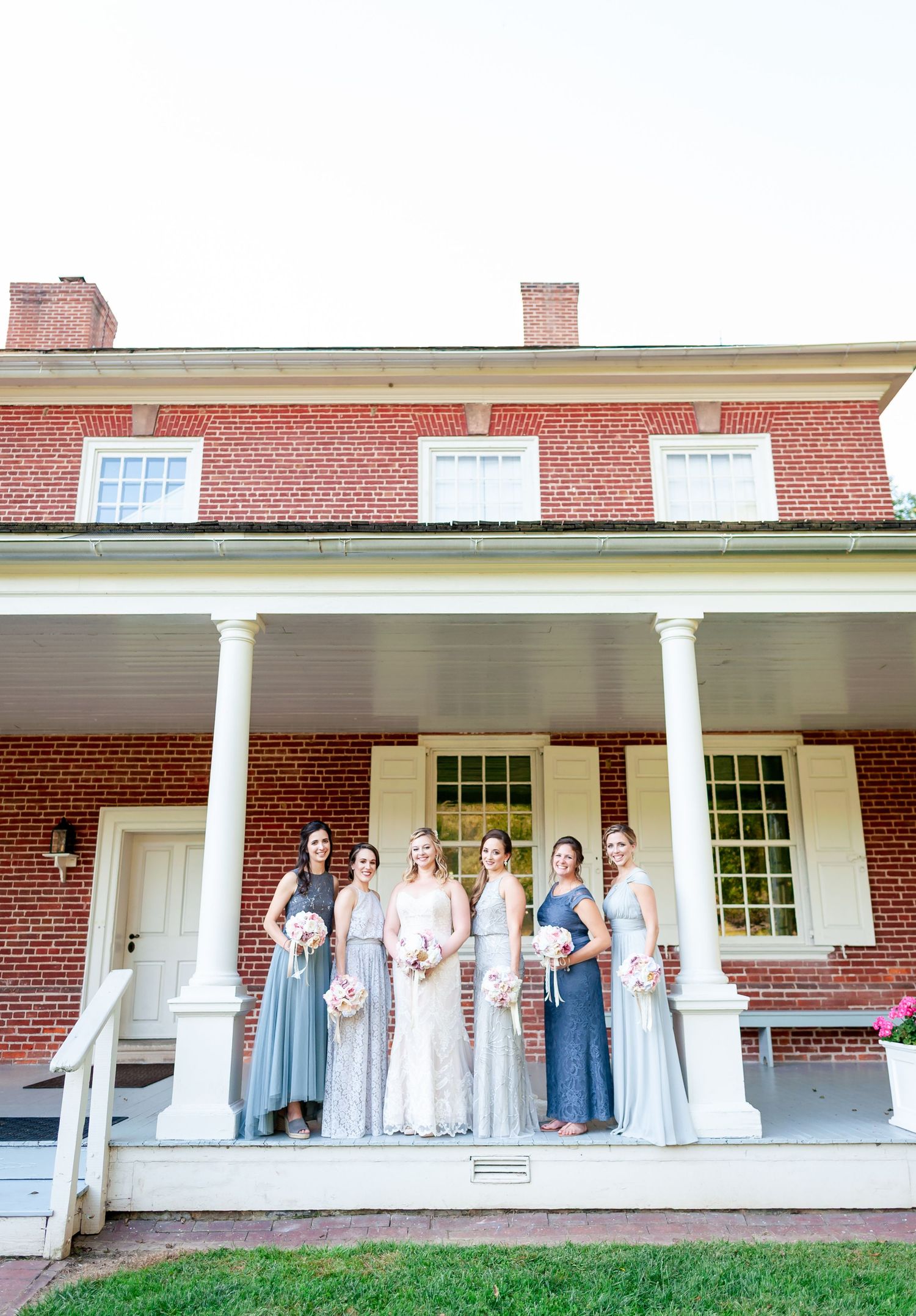 Wedding gathering arranged in front of historic brick building with white columns.