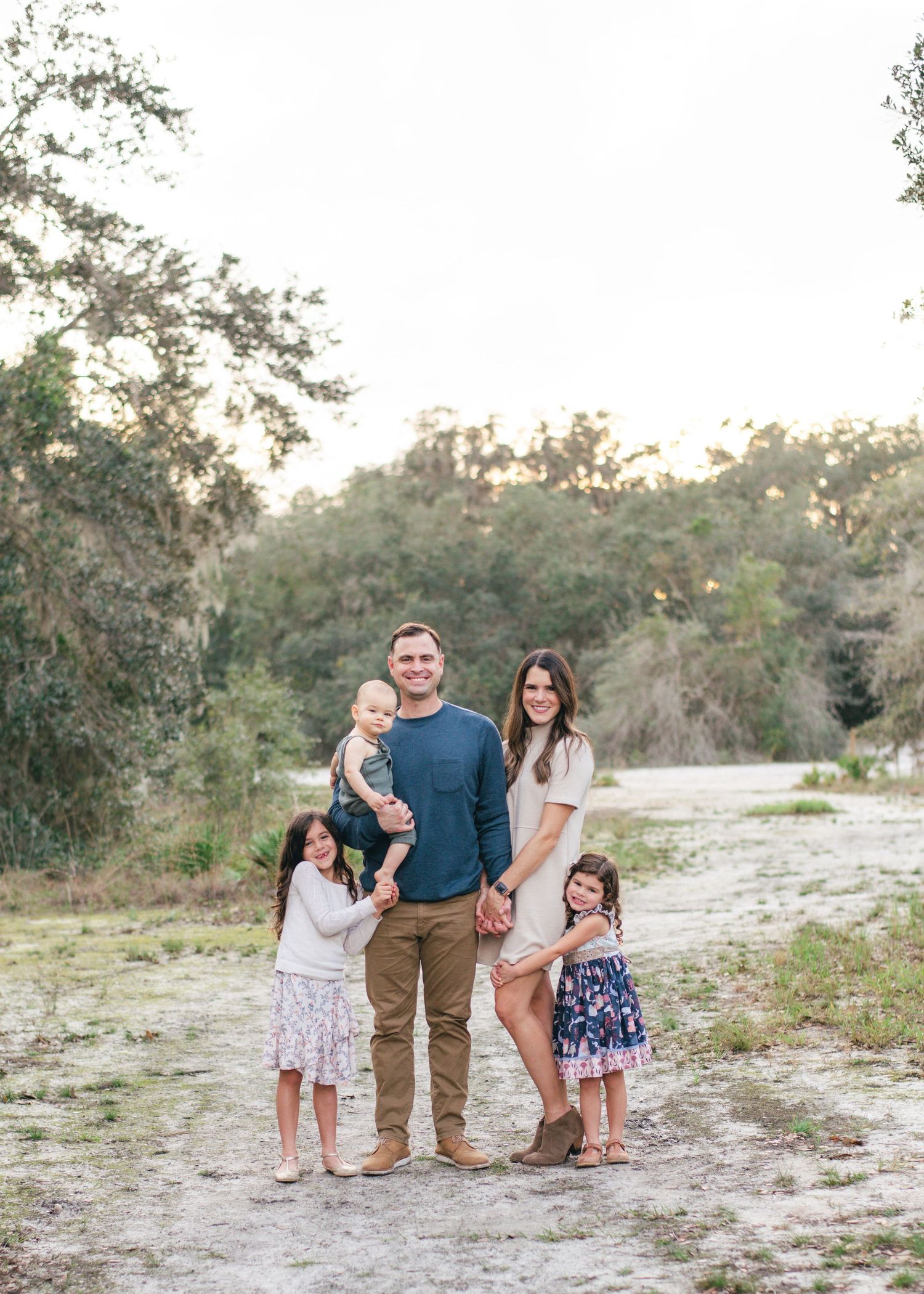 Family enjoys quality time together outdoors during sunset in a natural sandy setting.
