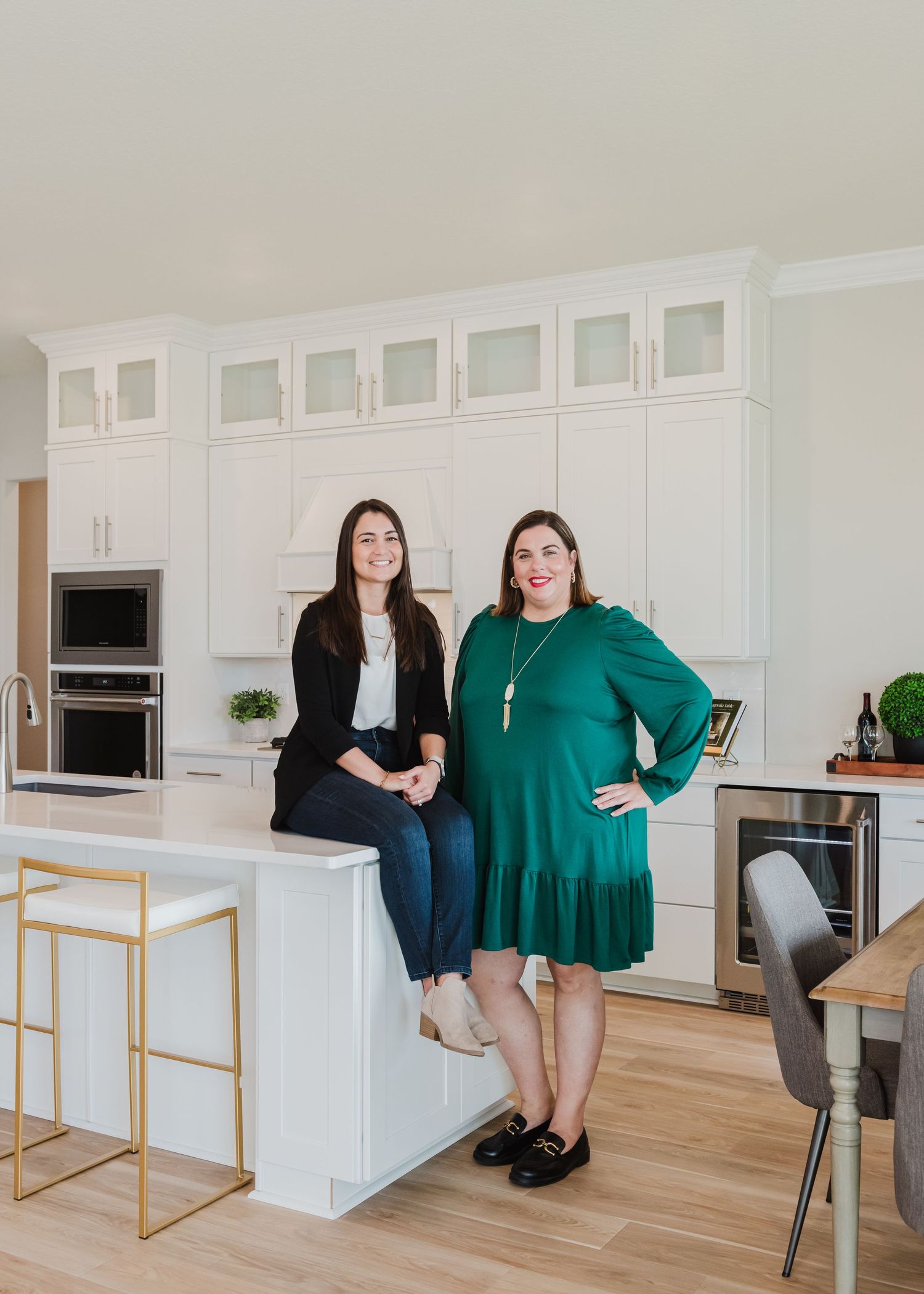 Two colleagues sitting together at modern kitchen counter with gold bar stools.