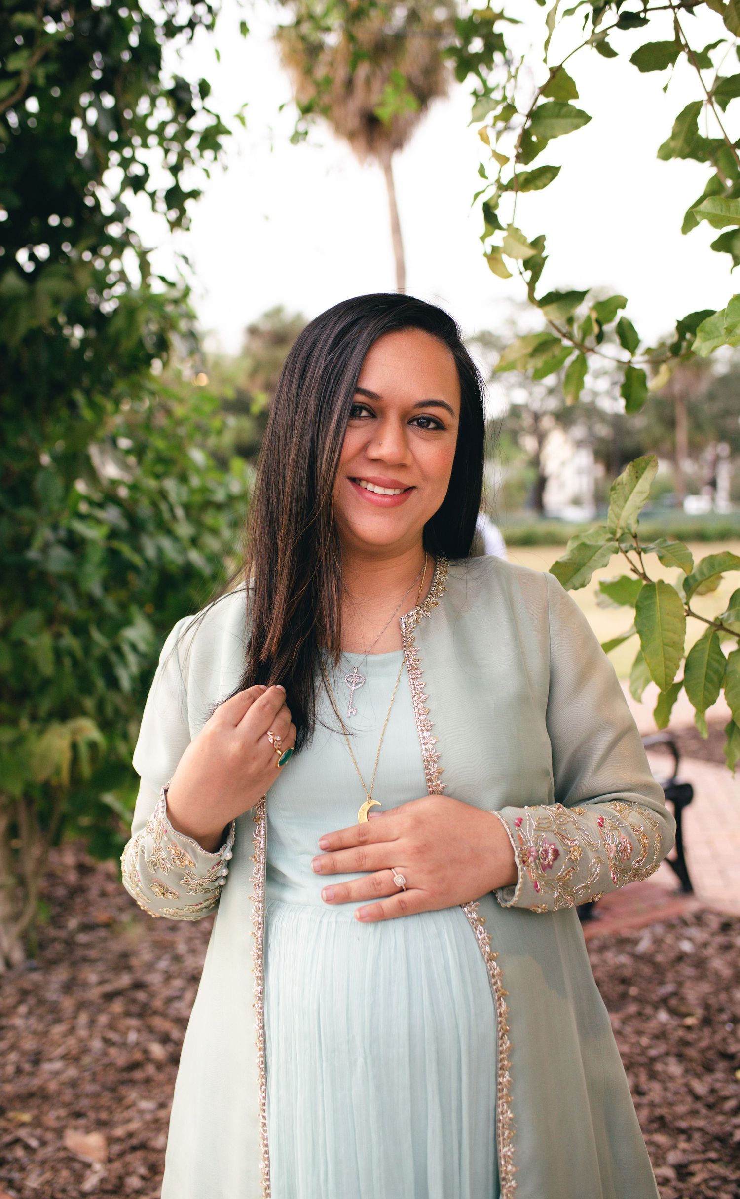 A series of outdoor portrait photos showing someone in a light mint green dress with embellished sleeves against a natural background.