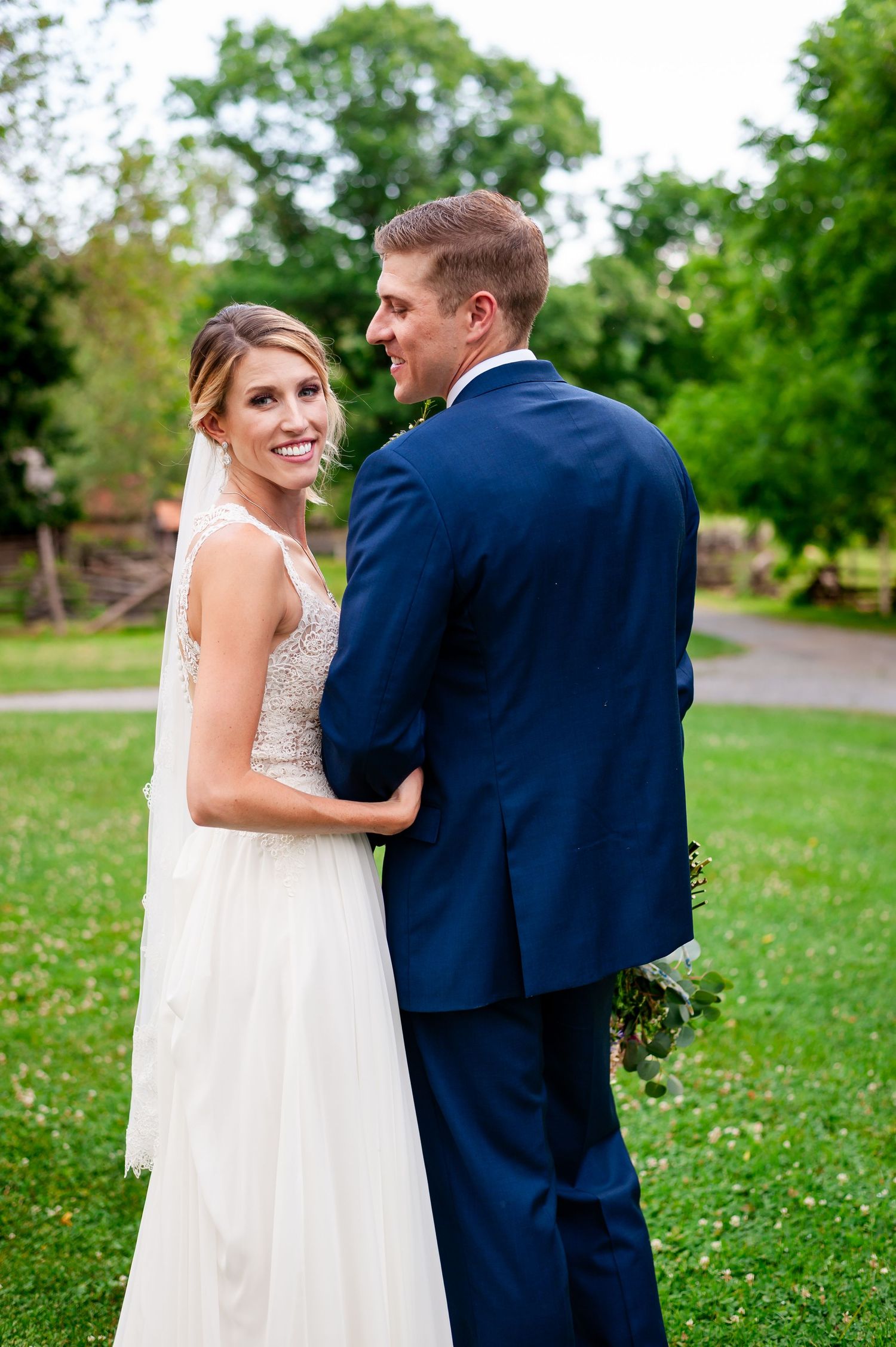 Wedding couple shares emotional first look moment on grassy lawn with scattered wildflowers.