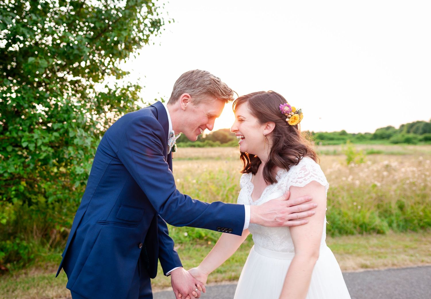 Newlyweds share joyful moment in countryside setting during golden hour.