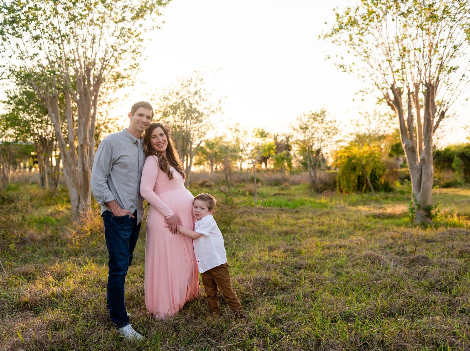 A couple enjoying a sunset together in a grassy field during the golden hour.