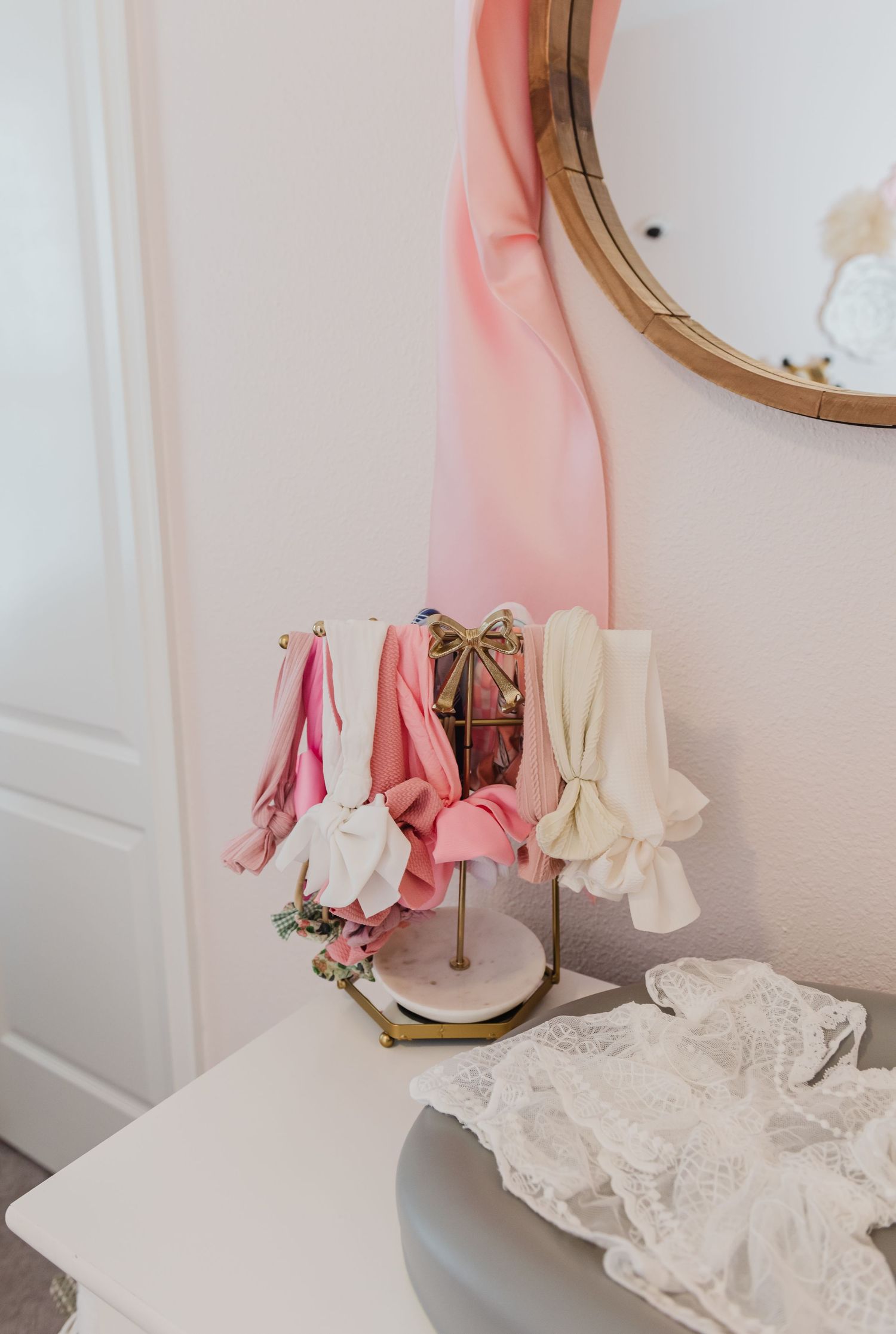 Vintage mirror and white dress details create romantic nursery vignette.