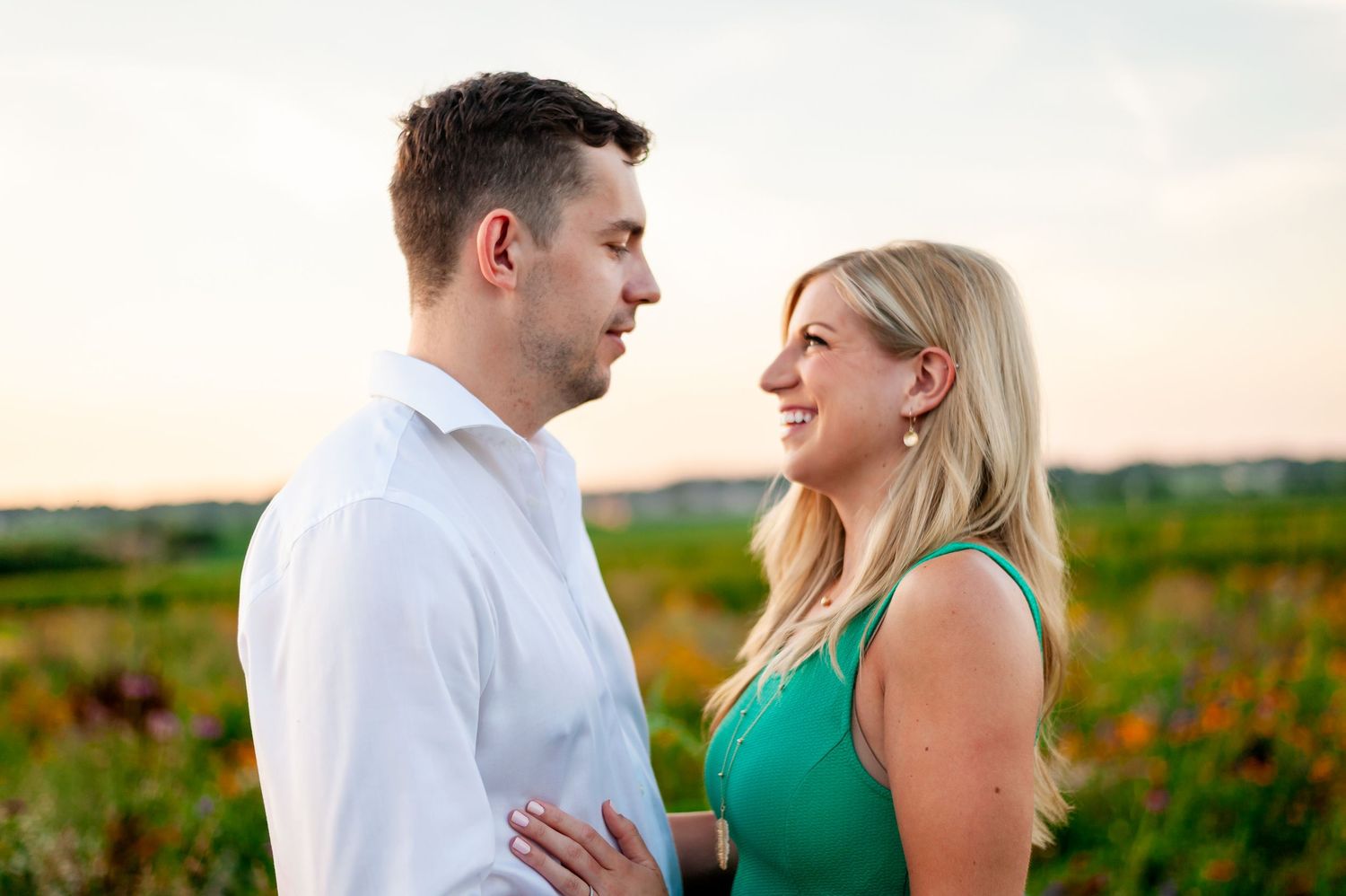 Couple shares tender moment while standing in blooming field of colorful wildflowers.