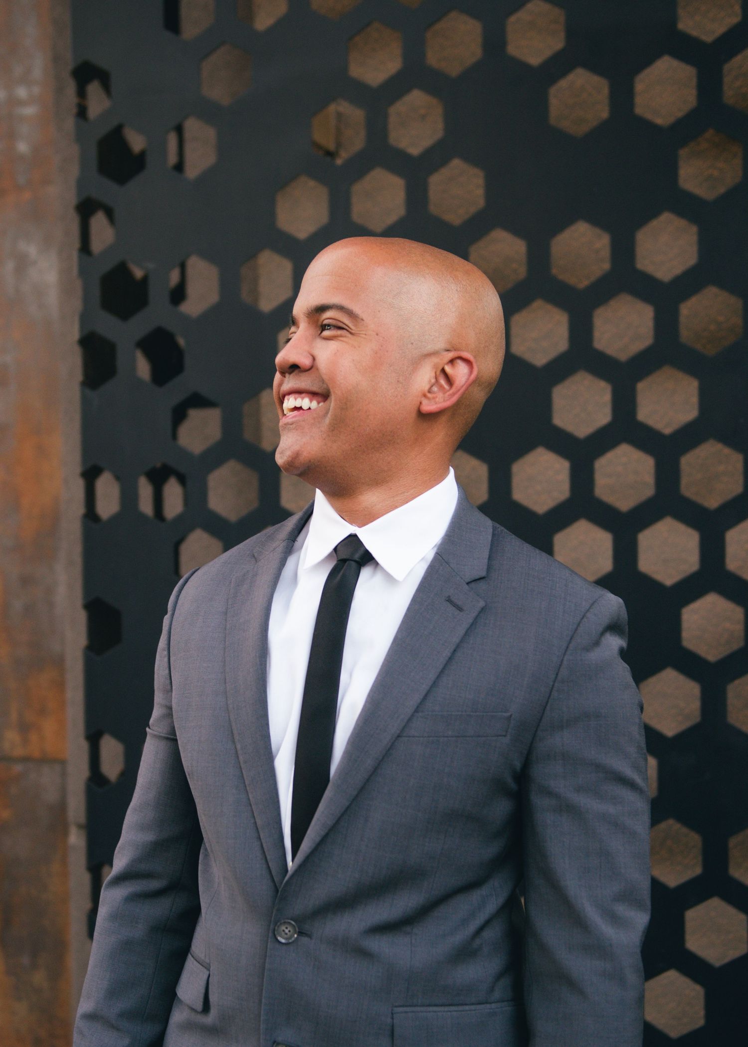 Professional headshots against a dark honeycomb pattern background in business attire.
