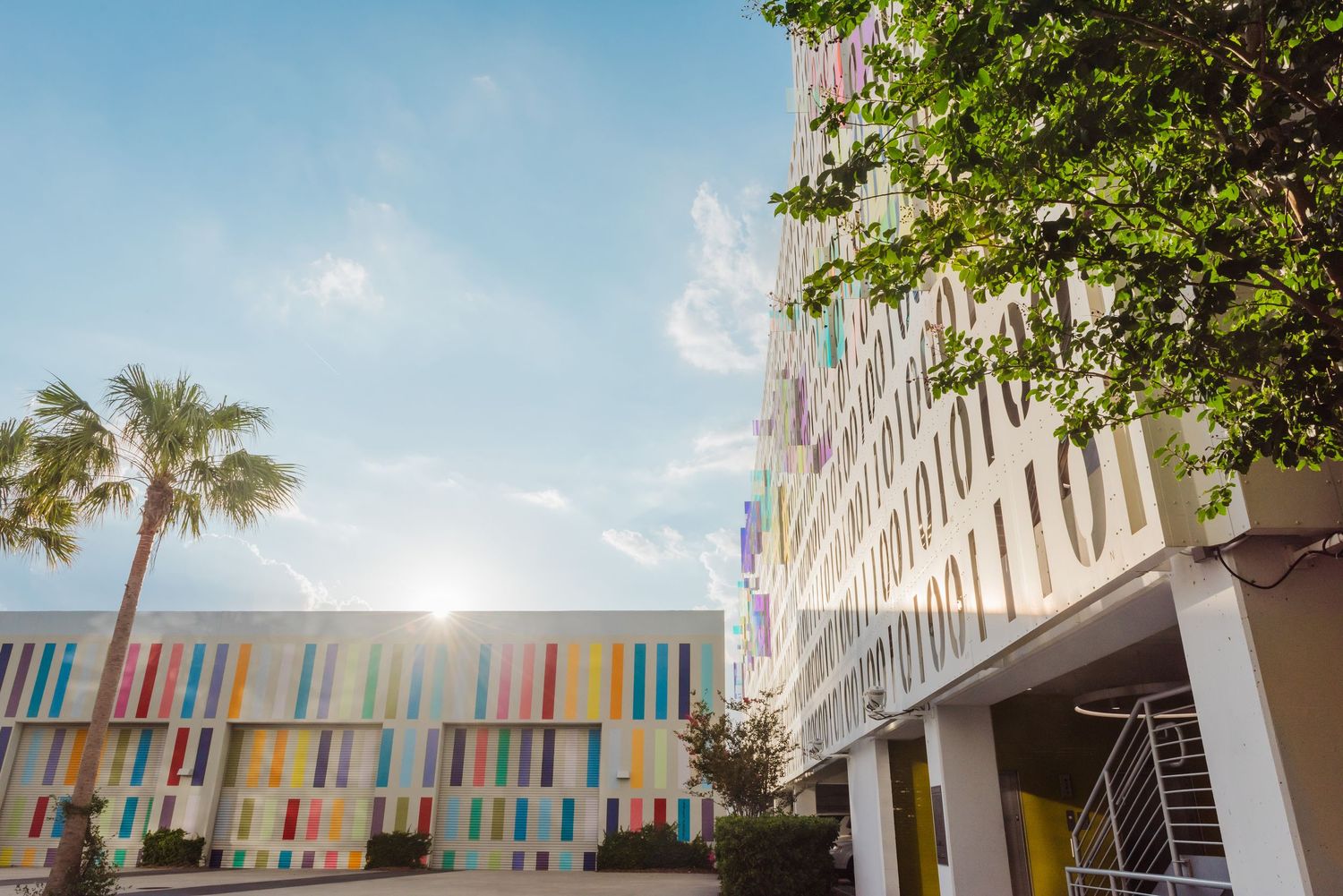 Modern building exterior with colorful striped walls and palm trees.