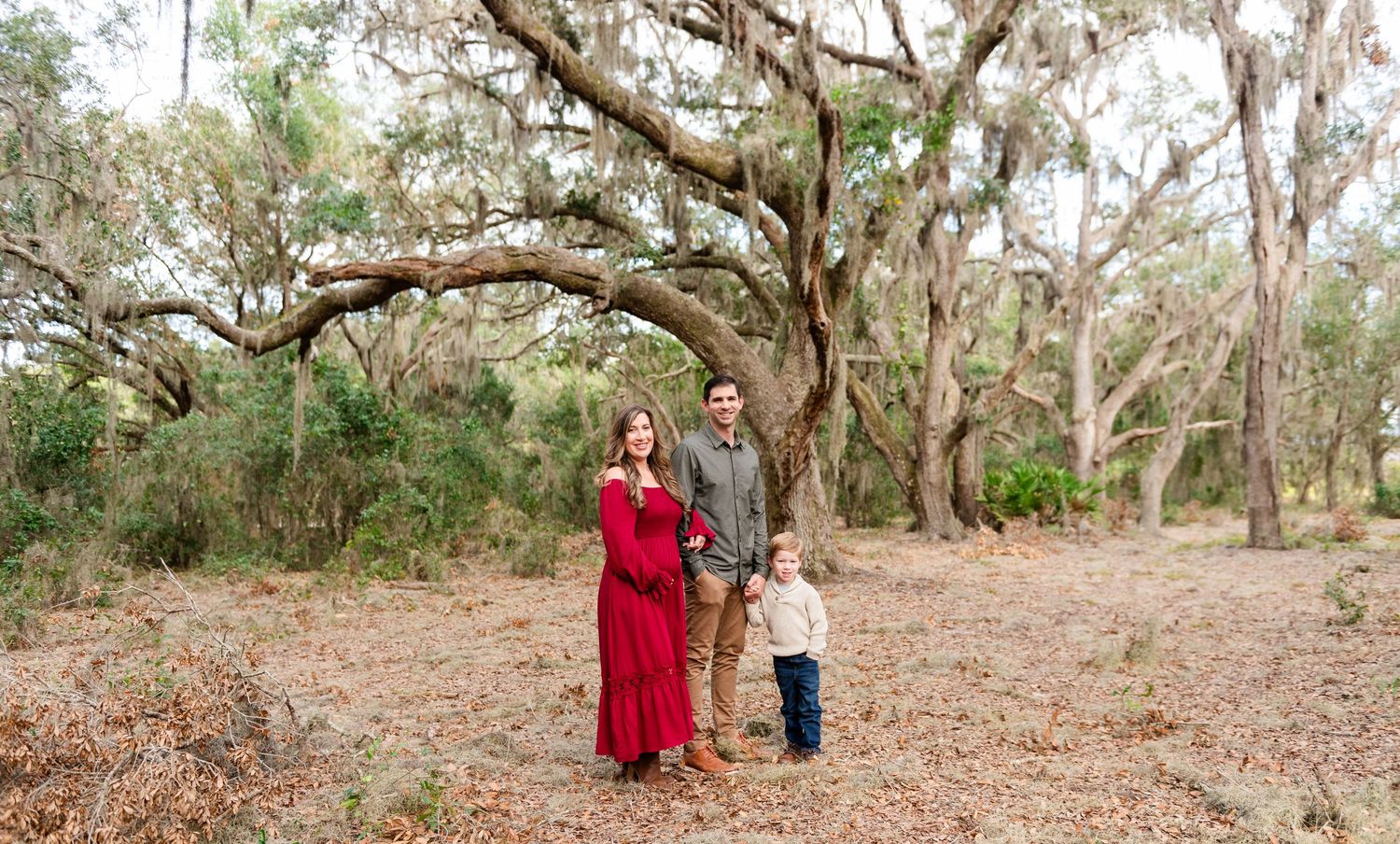 Family walking together through Spanish moss covered oak trees in an outdoor nature preserve during autumn.