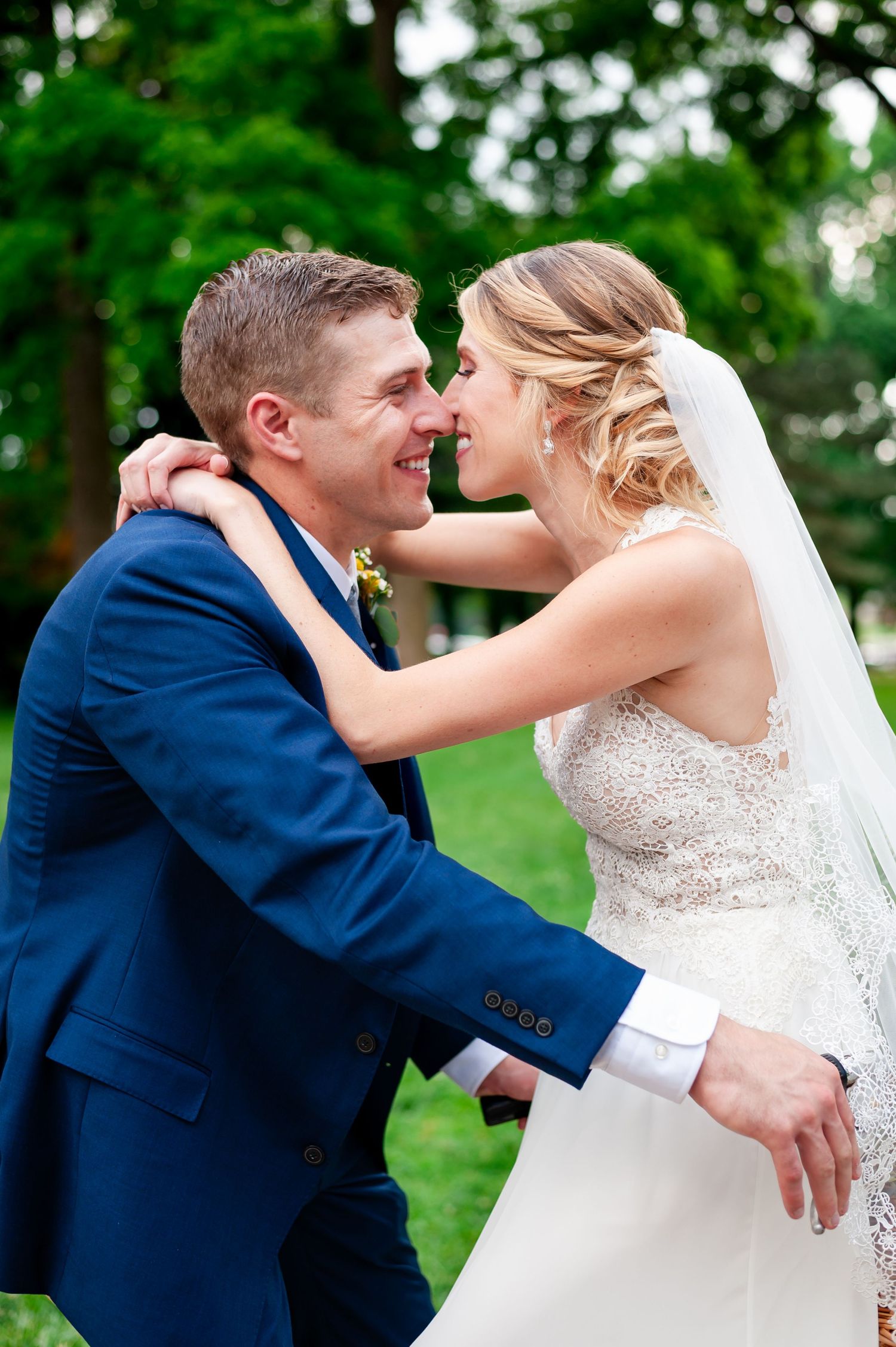 A playful wedding first look moment between a couple outdoors with the bride in white and groom in navy.
