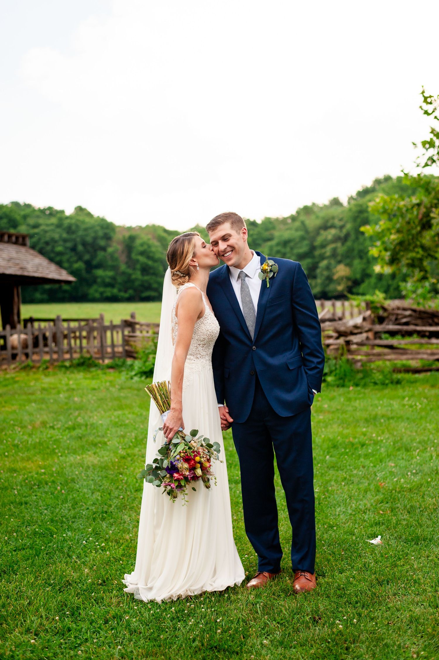Newlyweds share intimate moment in rustic outdoor setting with beautiful landscaping.