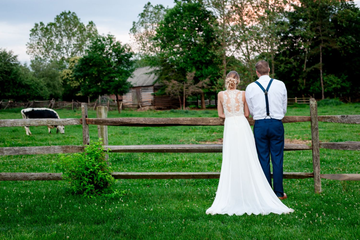 Wedding couple poses in lush green garden setting with long flowing white dress and suit.