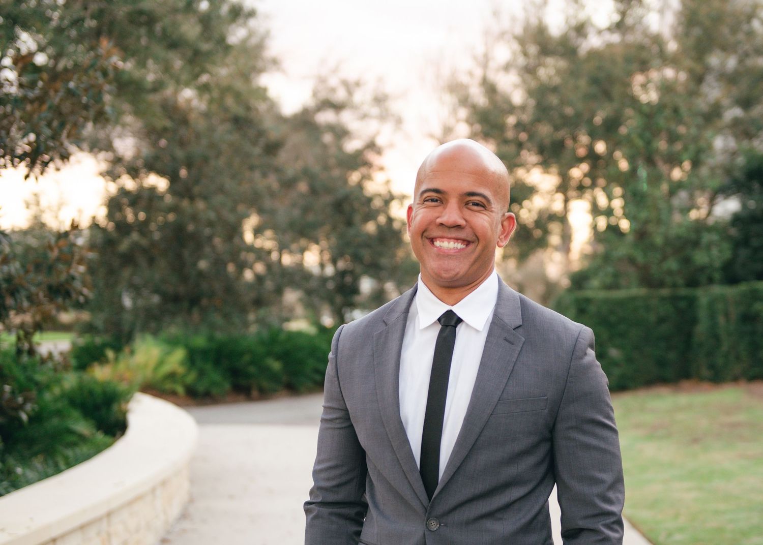 Formal portraits outdoors showing a well-dressed person in a grey suit and black tie.