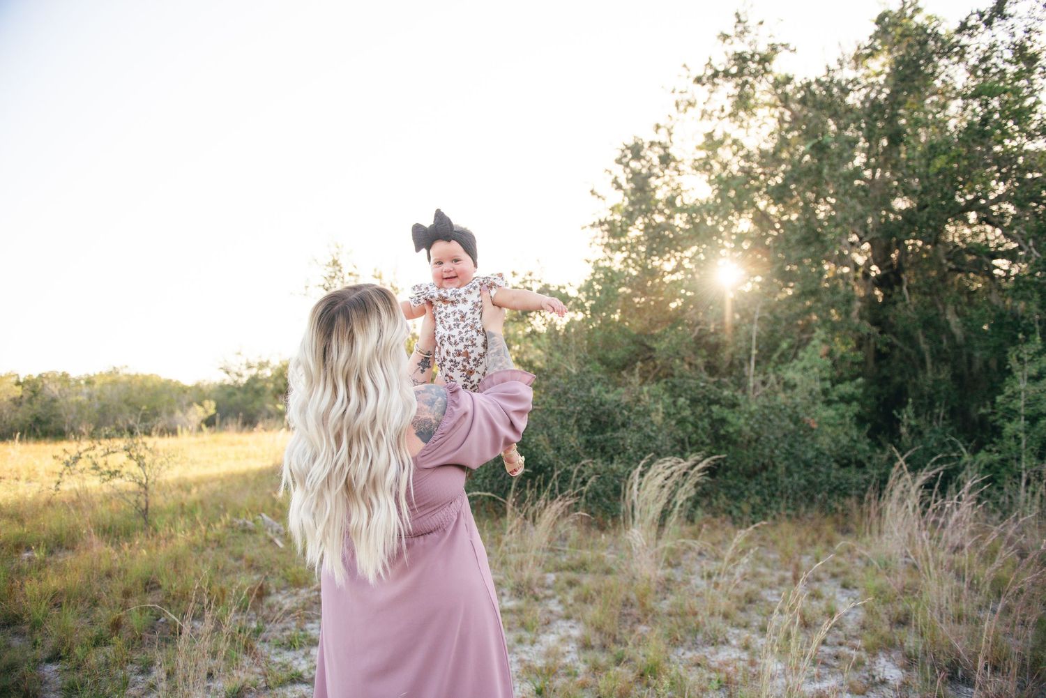 A romantic sunset photoshoot in a field with tall grass and golden light.
